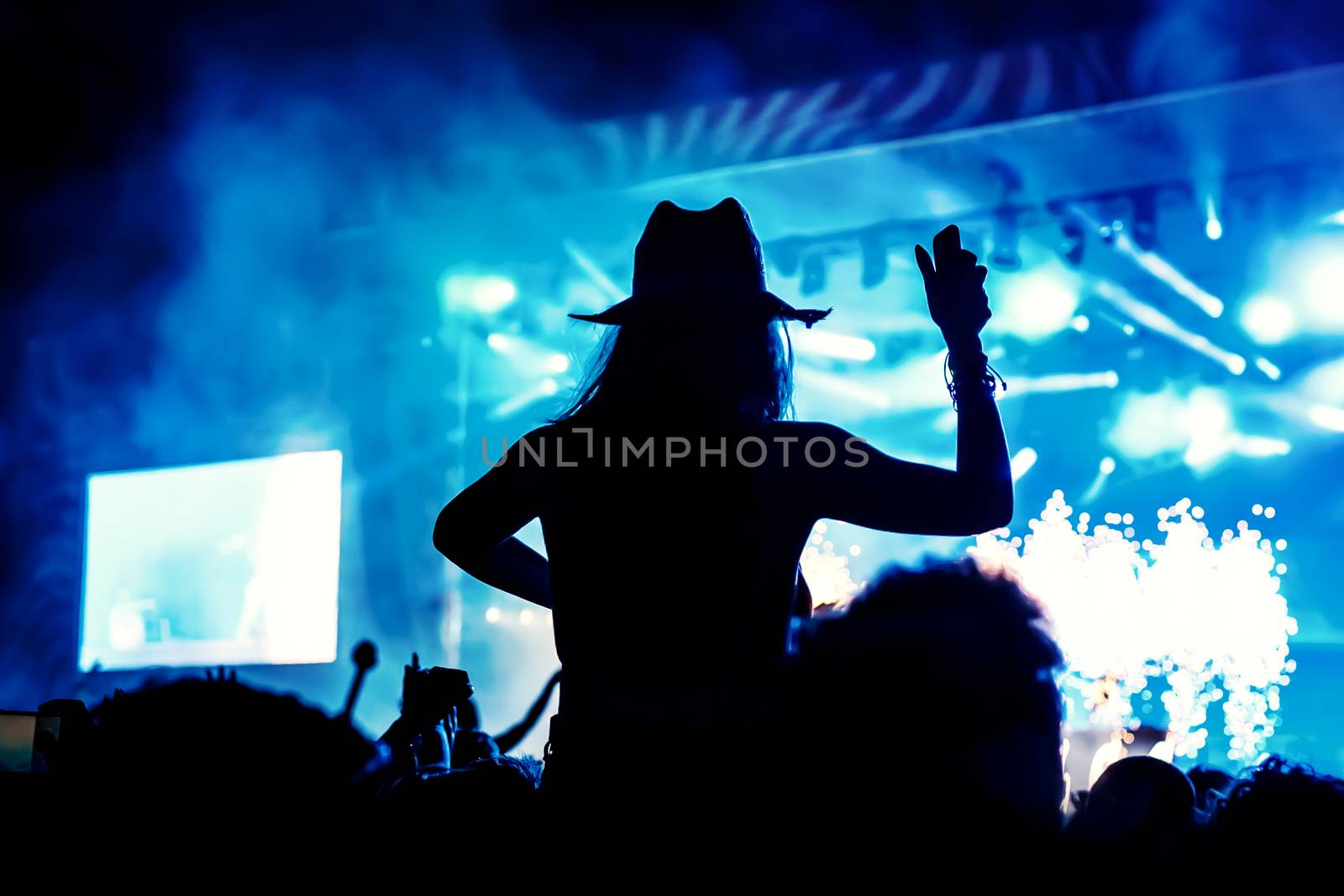 Silhouette of a girl with raised hands at a mass event. Party in a nightclub by 9parusnikov