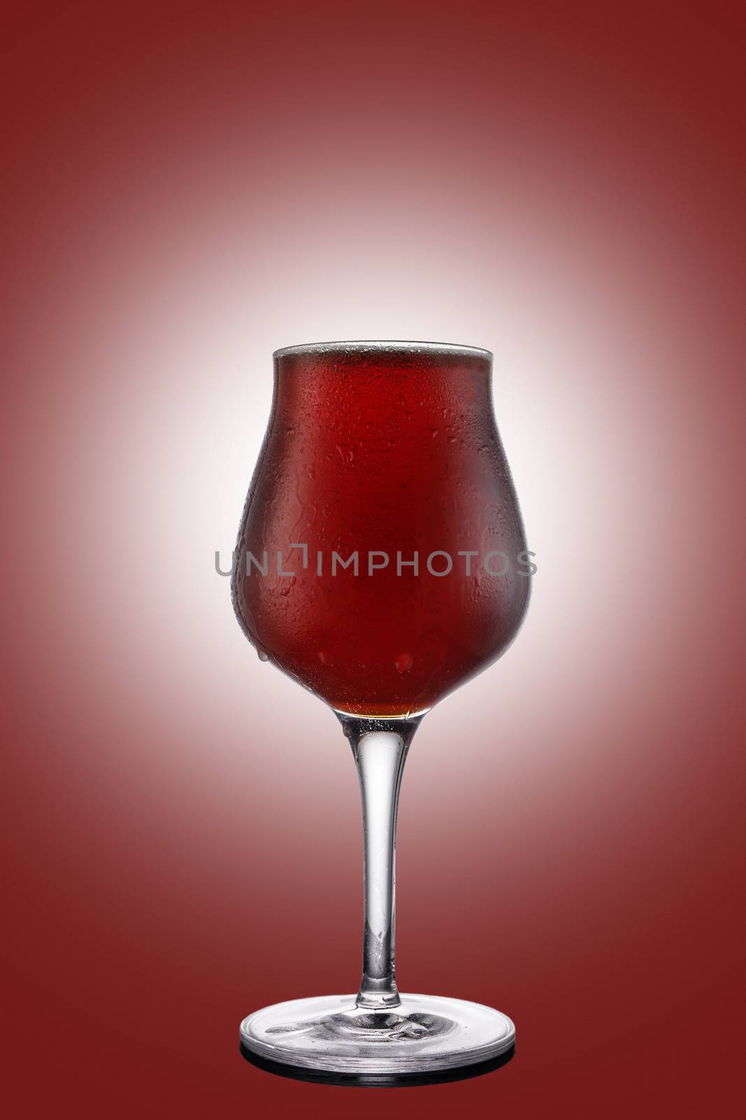 Red ale beer in tulip wineglass isolated on ruby background.