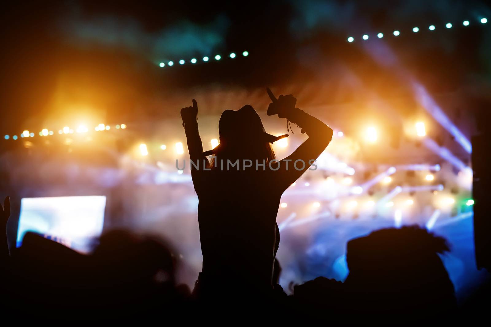 Silhouette of a girl with raised hands at a mass event. Party in a nightclub by 9parusnikov