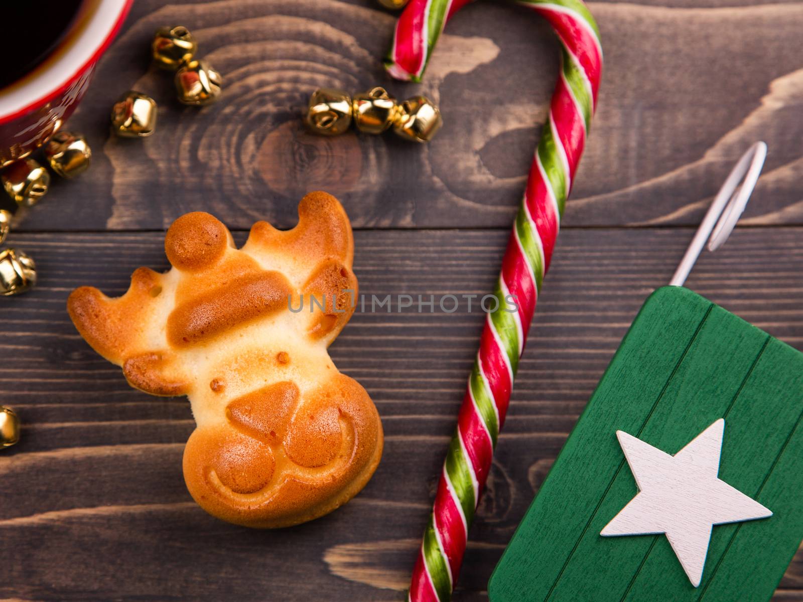 New Year gingerbread in the form of a deer. Christmas composition with gingerbread, sweets and decor. Background with tasty cookies and Christmas decor on wooden table. Top view, flat lay, copy space.