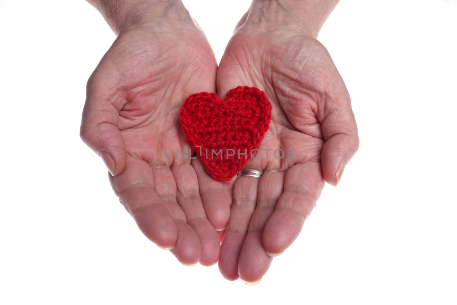 Old woman's hands giving woollen heart 