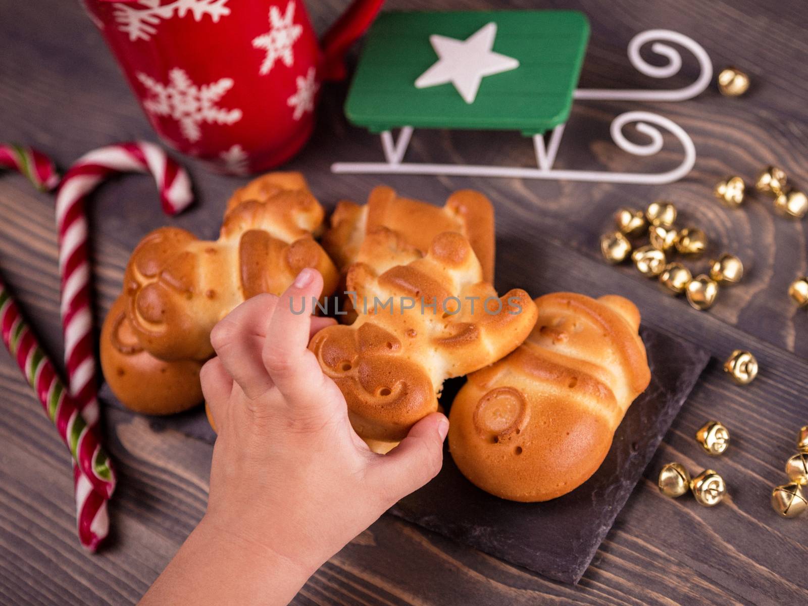 Christmas cookies homemade on the brown wooden background. Christmas background. Homemade cookies baked to Christmas. Children's hand takes gingerbread. Top view, closeup.