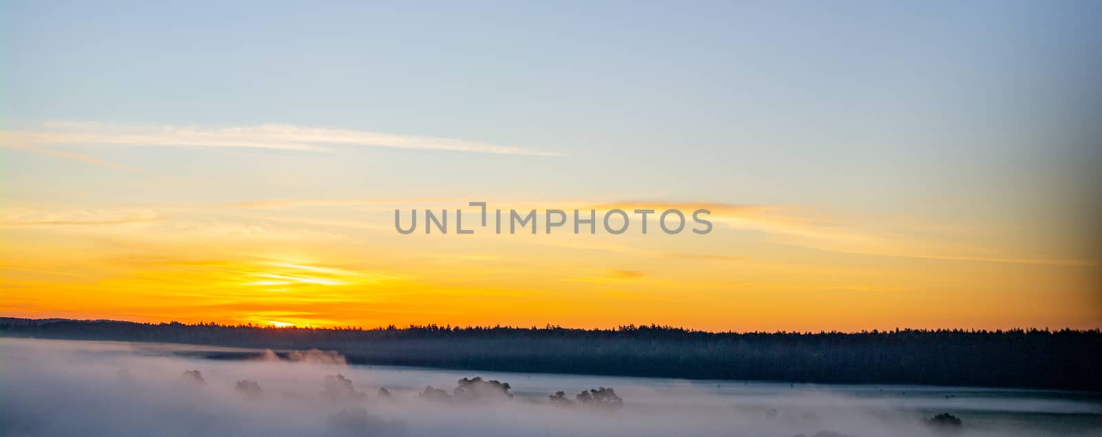 Predawn morning fog and orange-blue sky with clouds.