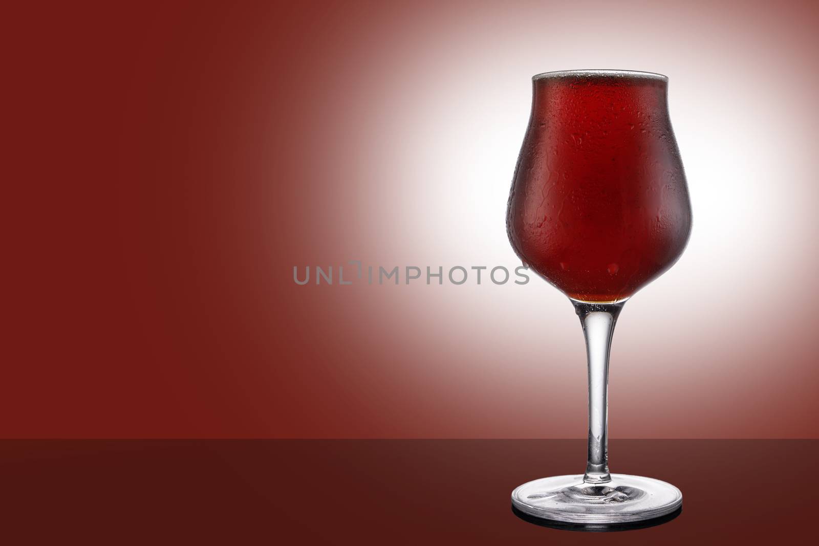 Red ale beer in tulip wineglass isolated on ruby background.