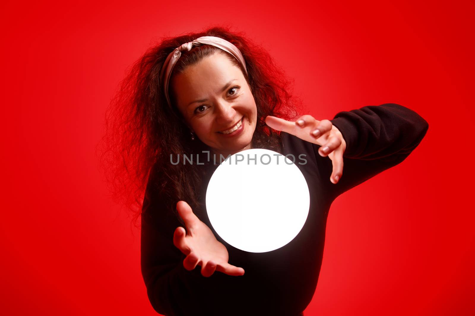 Smiling girl holding a glowing ball in her hands Red background