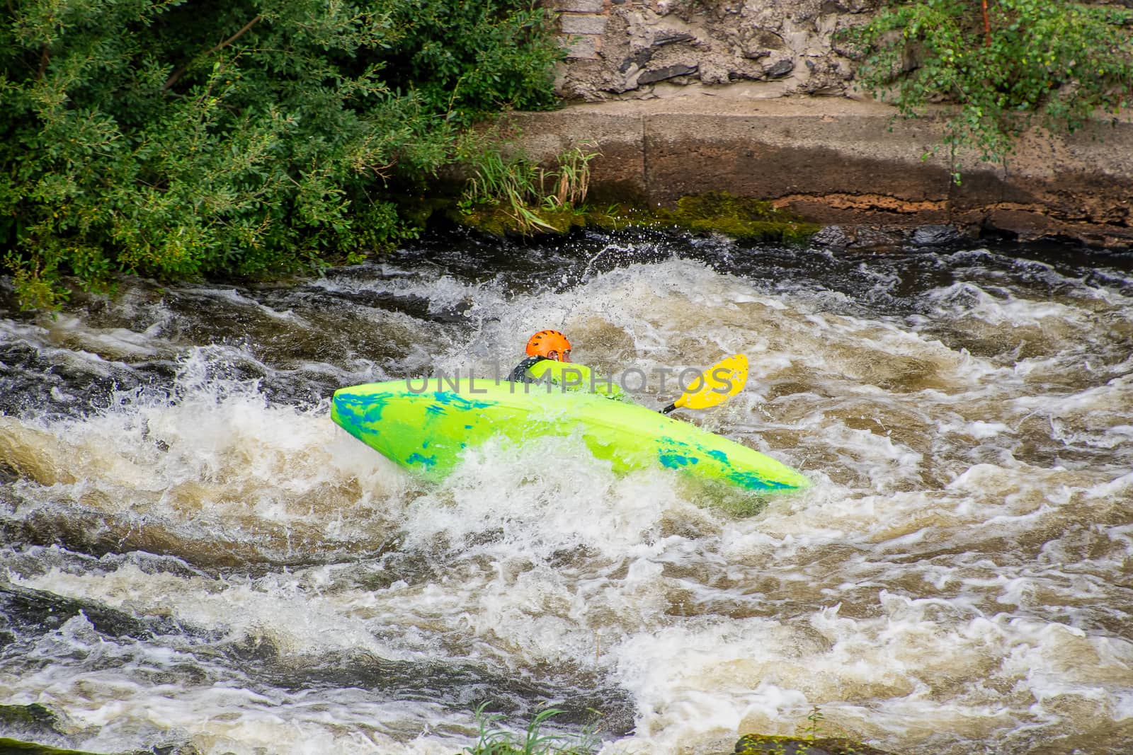 White water kayaker canoeing through rapids and capsizing on the River Dee