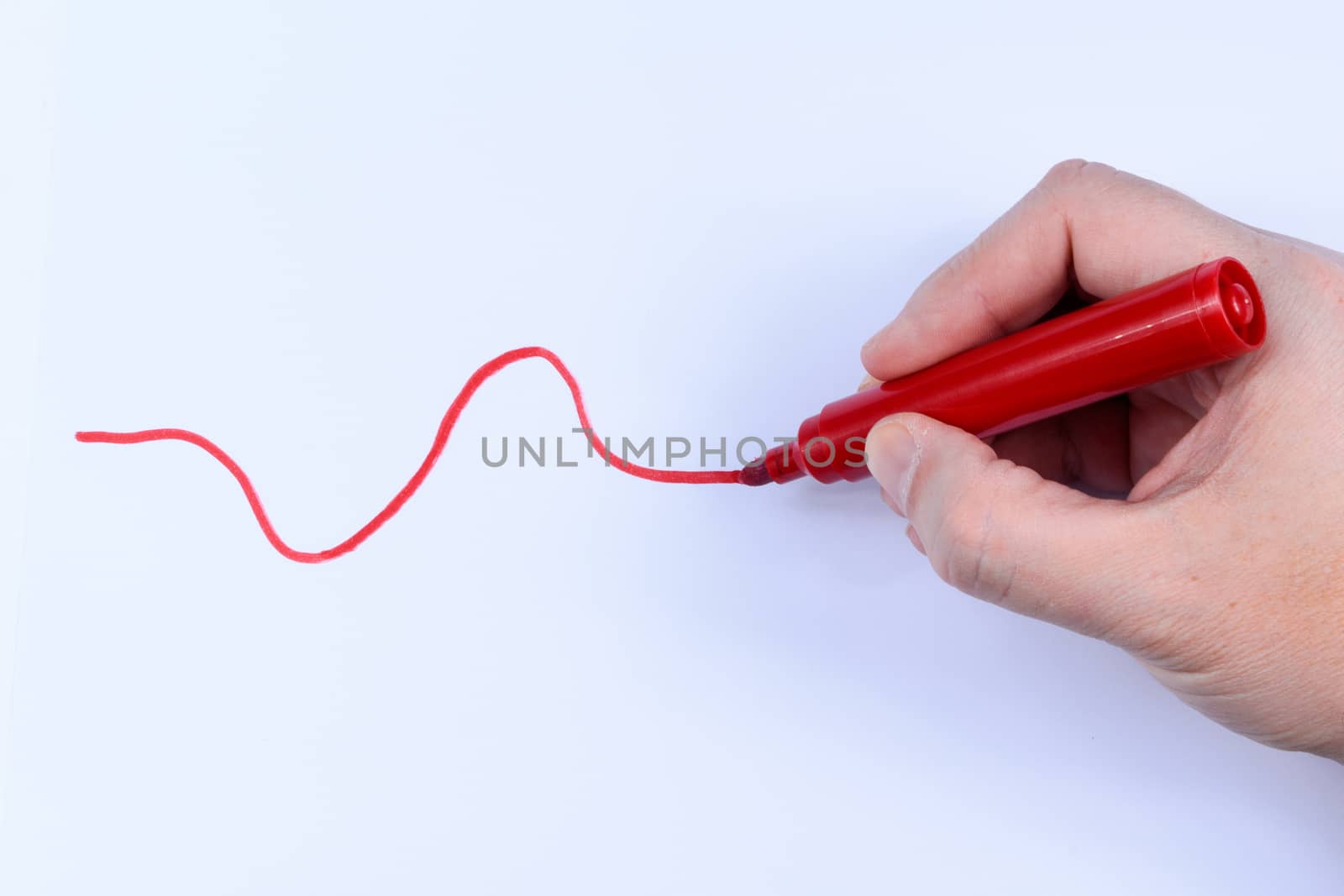 Hand holding a red  pen drawing a wavey line isolated on white background