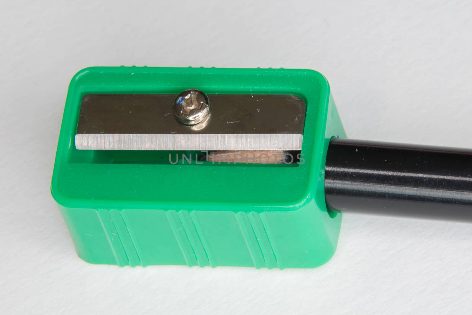 Green pencil sharpener with a black pencil on a white background