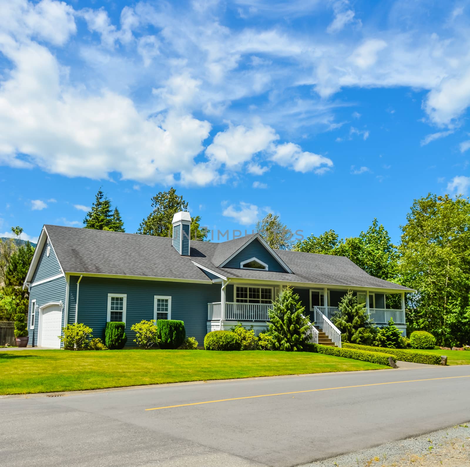 Big residential house on a country side with asphalt road in front. Big family home in British Columbia, Canada