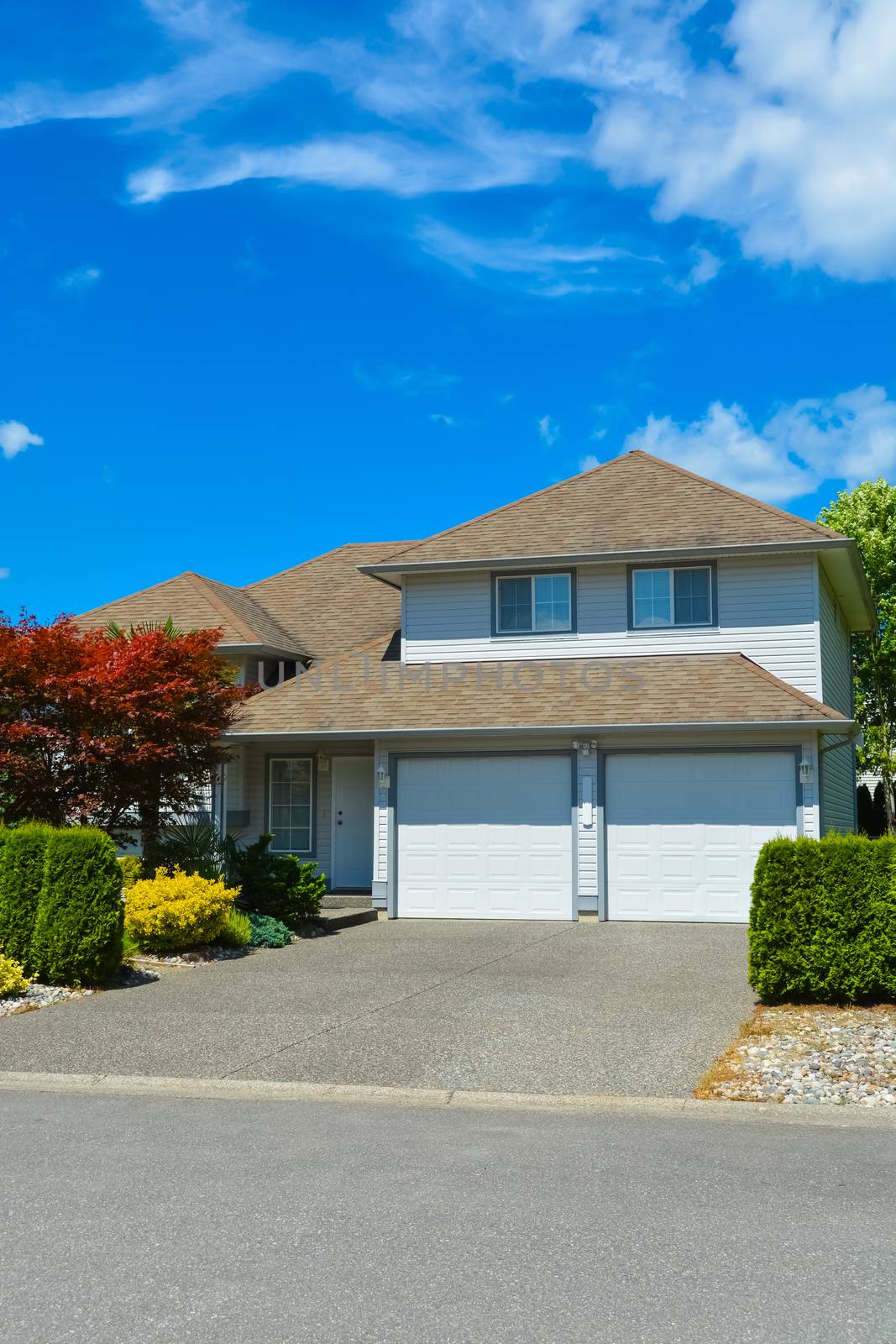 Driveway of average residential house on sunny day on blue sky background