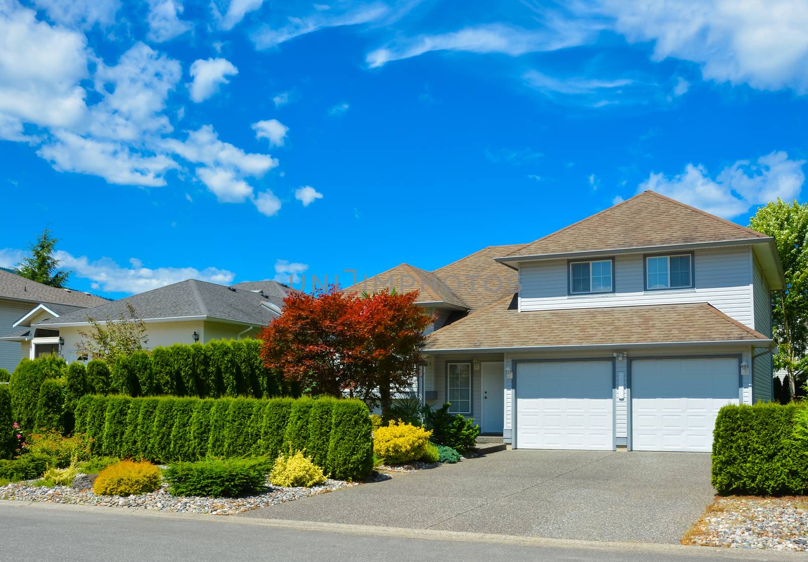 Driveway of average residential house on sunny day on blue sky background