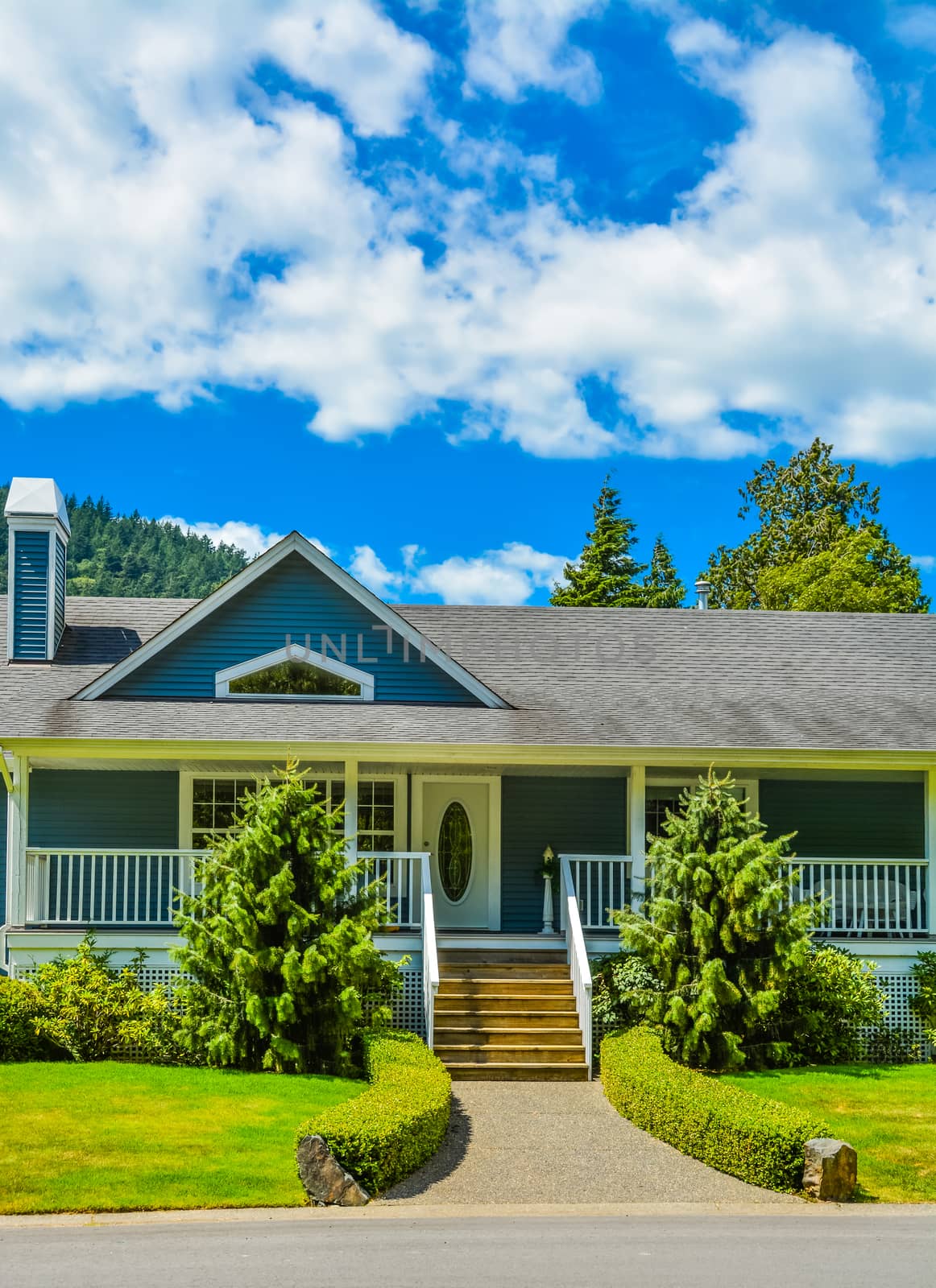 Entrance of big residential house on a country side with asphalt road in front. Big family home in British Columbia, Canada