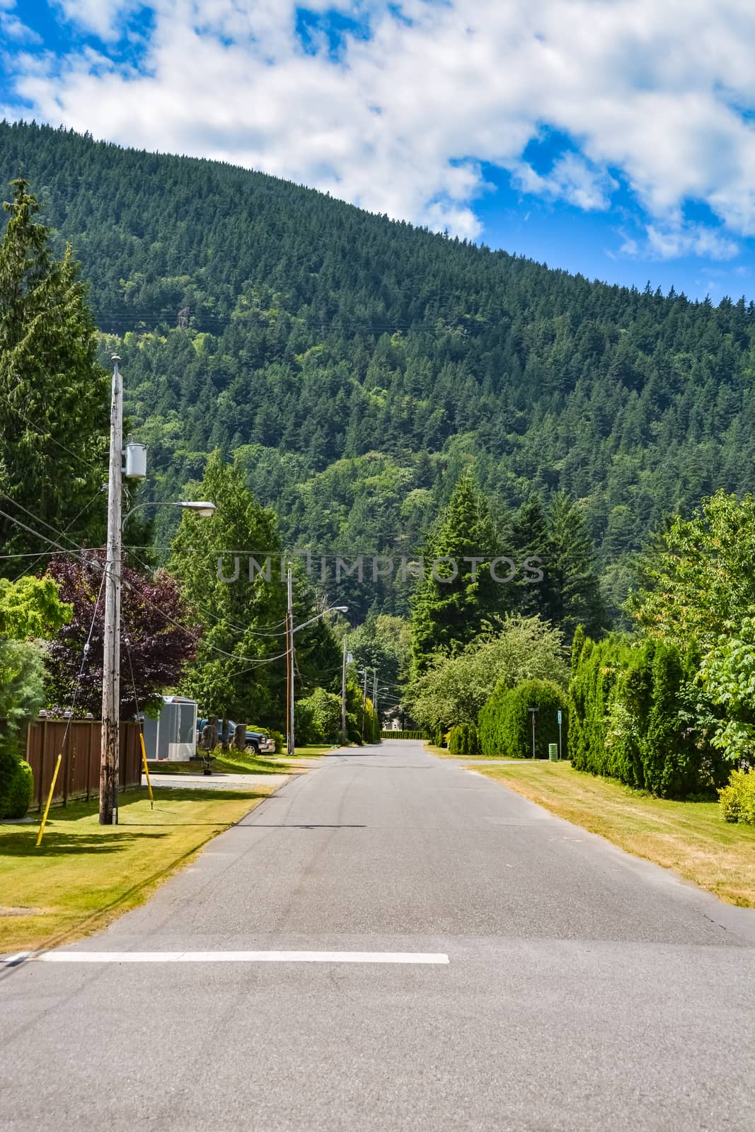 Asphalt road in rural town leading toward a mountain