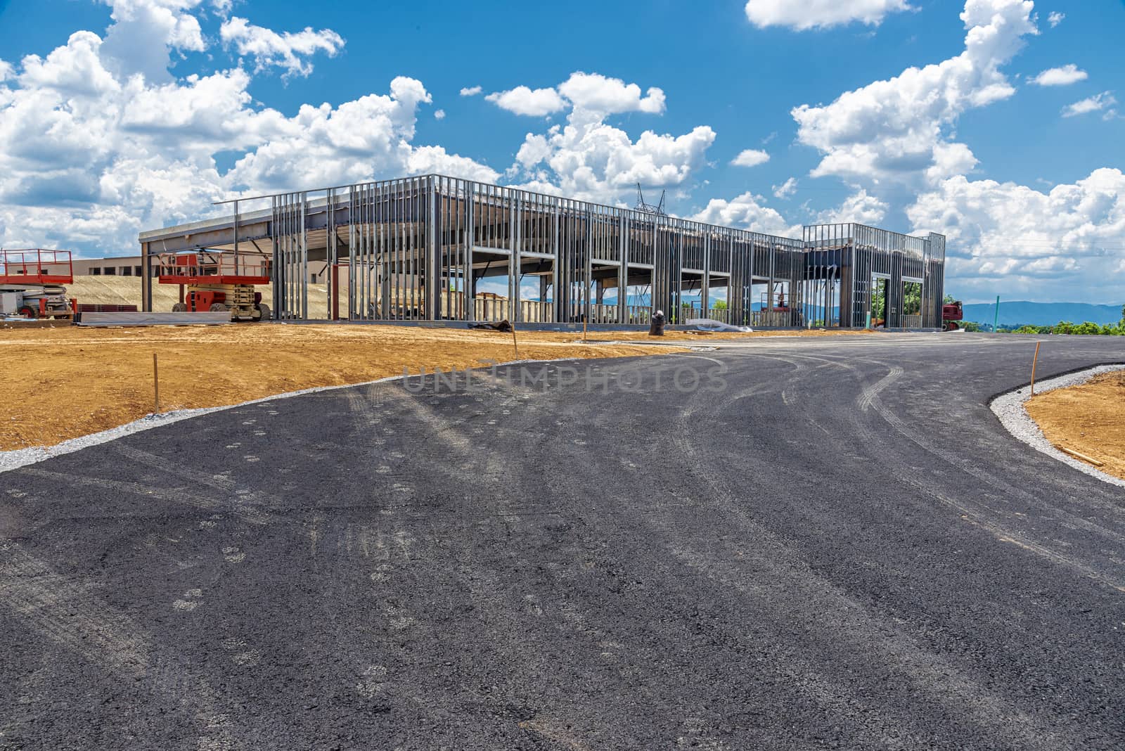 Horizontal shot of commercial building under construction with a drive running in front of it. 