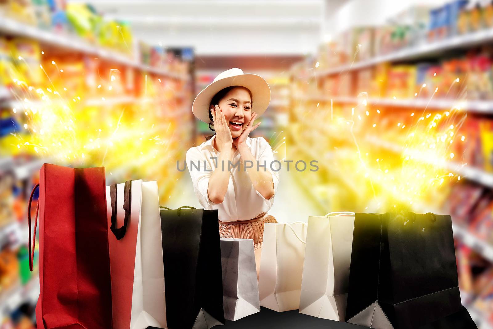 a happy shopaholic woman opening shopping bags in the shopping m by Surasak