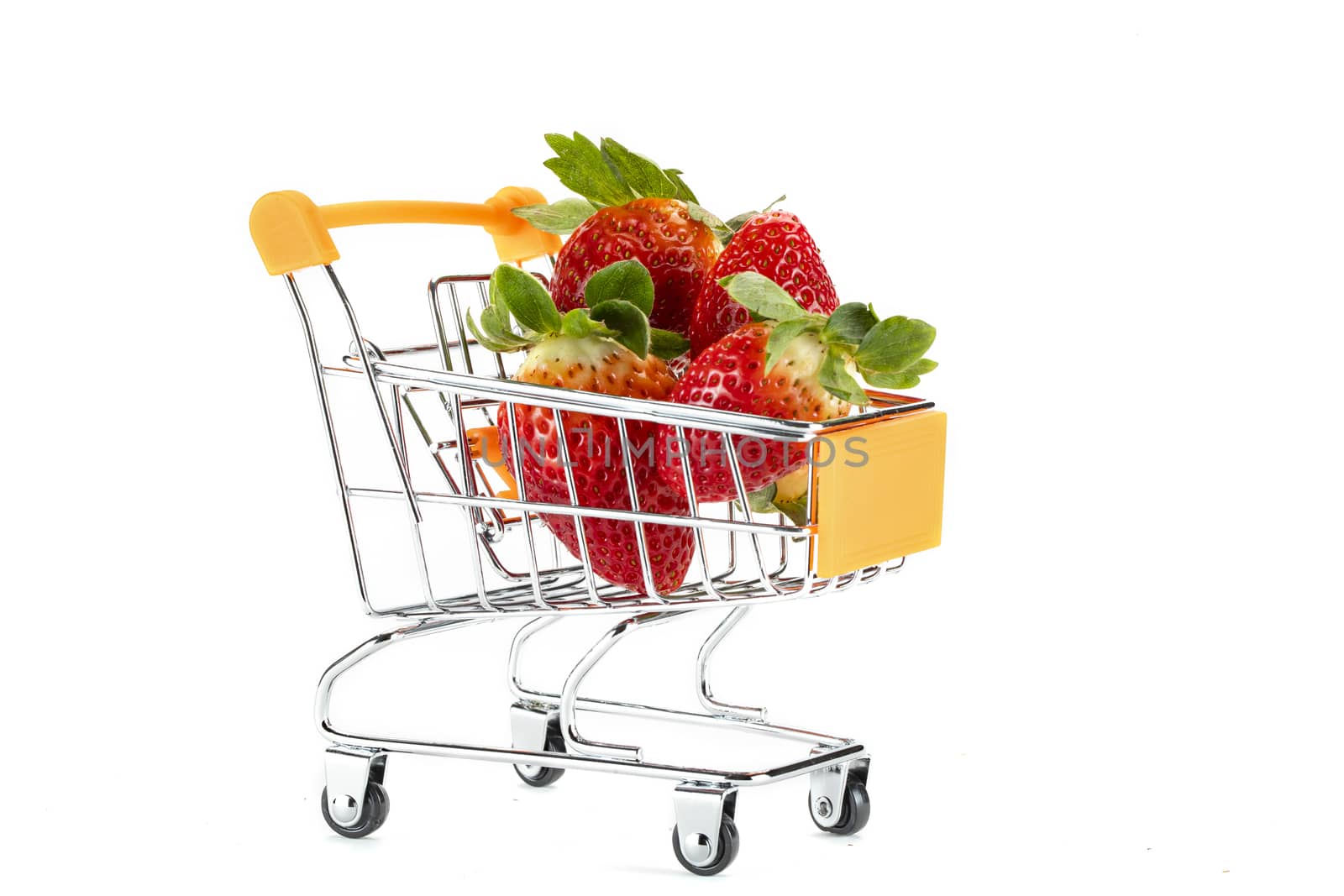 A bunch of red fresh strawberries on a toy shopping cart. Isolated on white background.