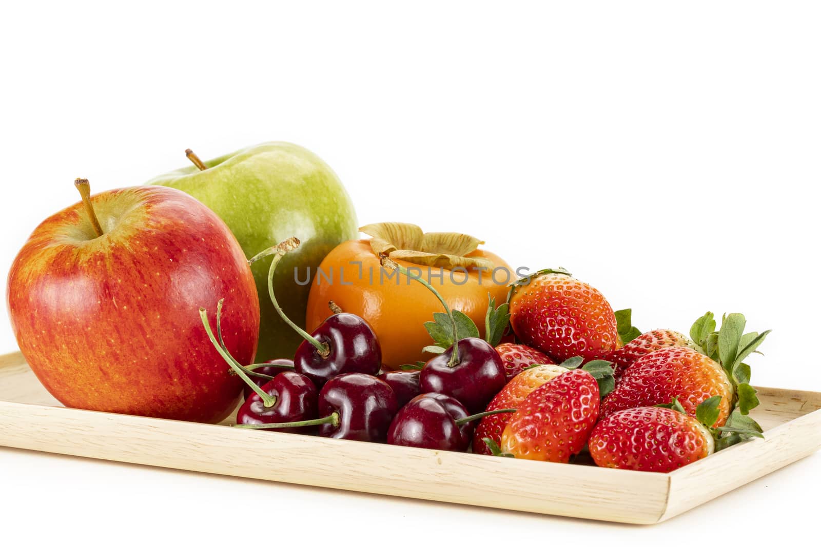Fresh ripe red, and green apples, persimmon, cherries and strawberries on a wooden plate, isolated on a white background.