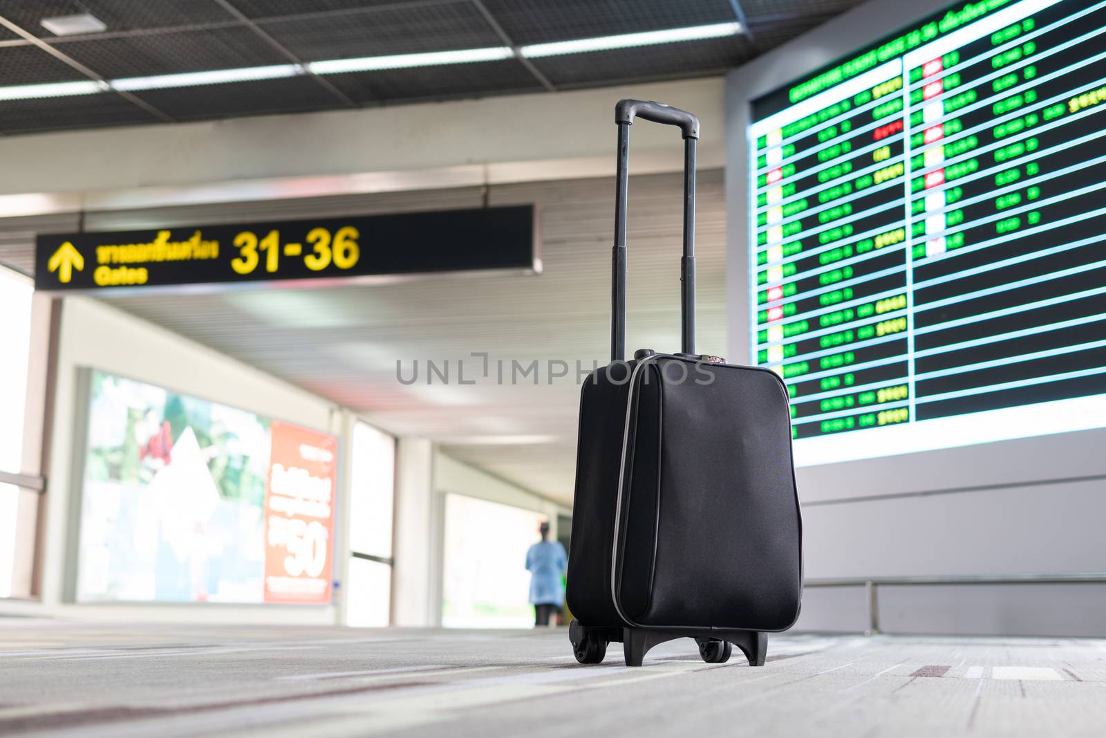 Passenger luggage wait and look at terminal gate information board checking for her flight in international airport. Suitcases in the departure lounge, holiday vacation concept, traveler suitcases