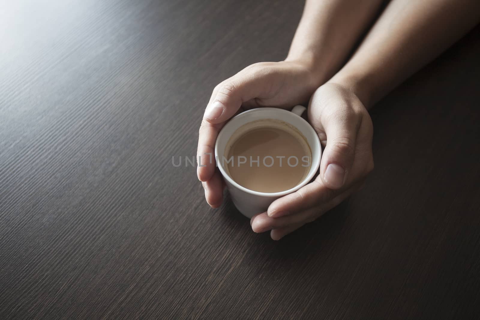 Hands hold a hot cup of coffee on a table