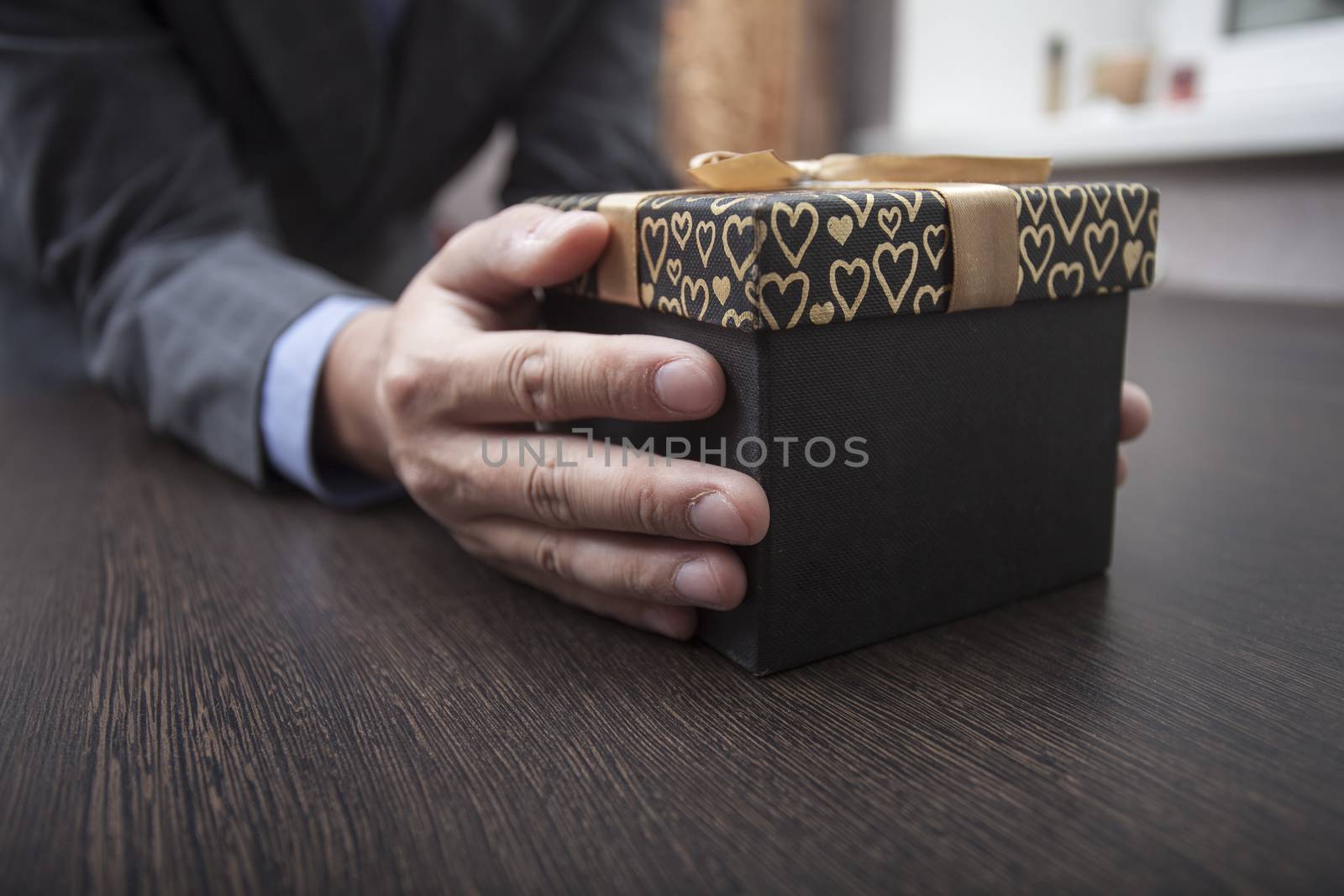 Man's hands keep a box in a business suit wrapped up by a bow