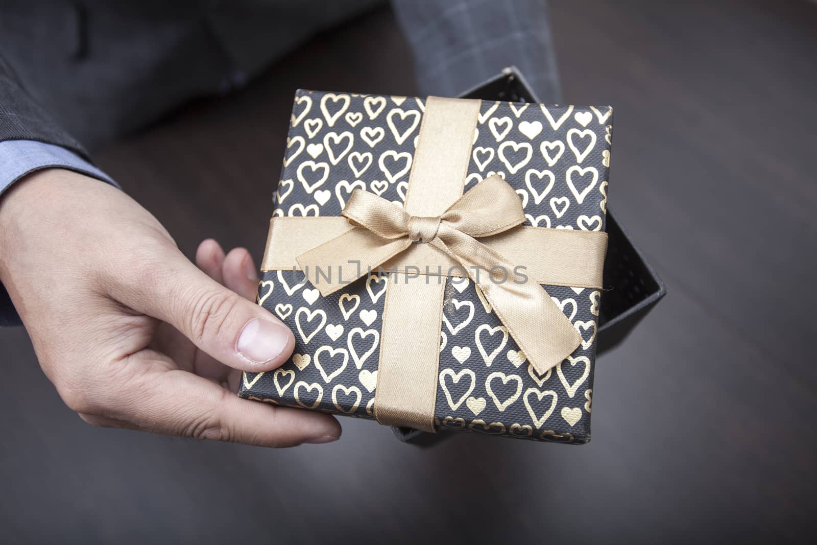 Man's hands keep a half open box in a business suit wrapped up by a bow