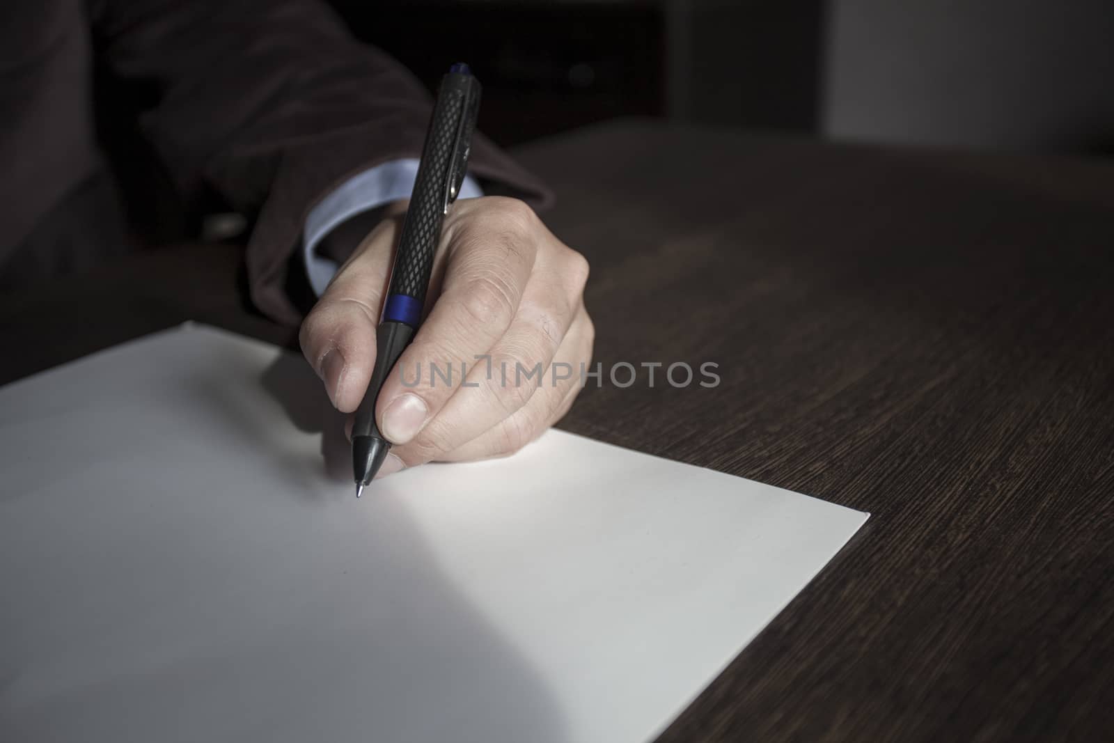 Man's hands keep the handle in a business suit over a sheet of paper