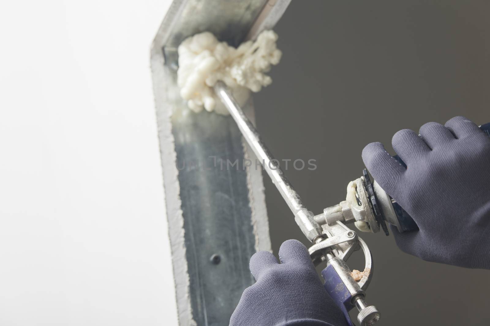 Construction site worker using a can of expanding foam to fix a doorway