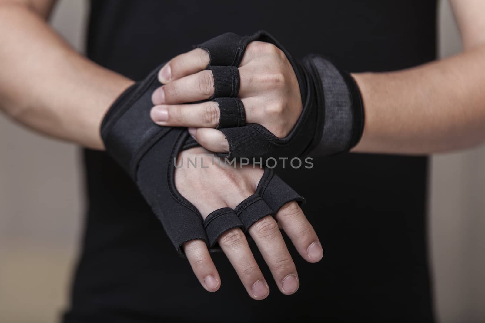 Man's hands put on sports gloves for a gym