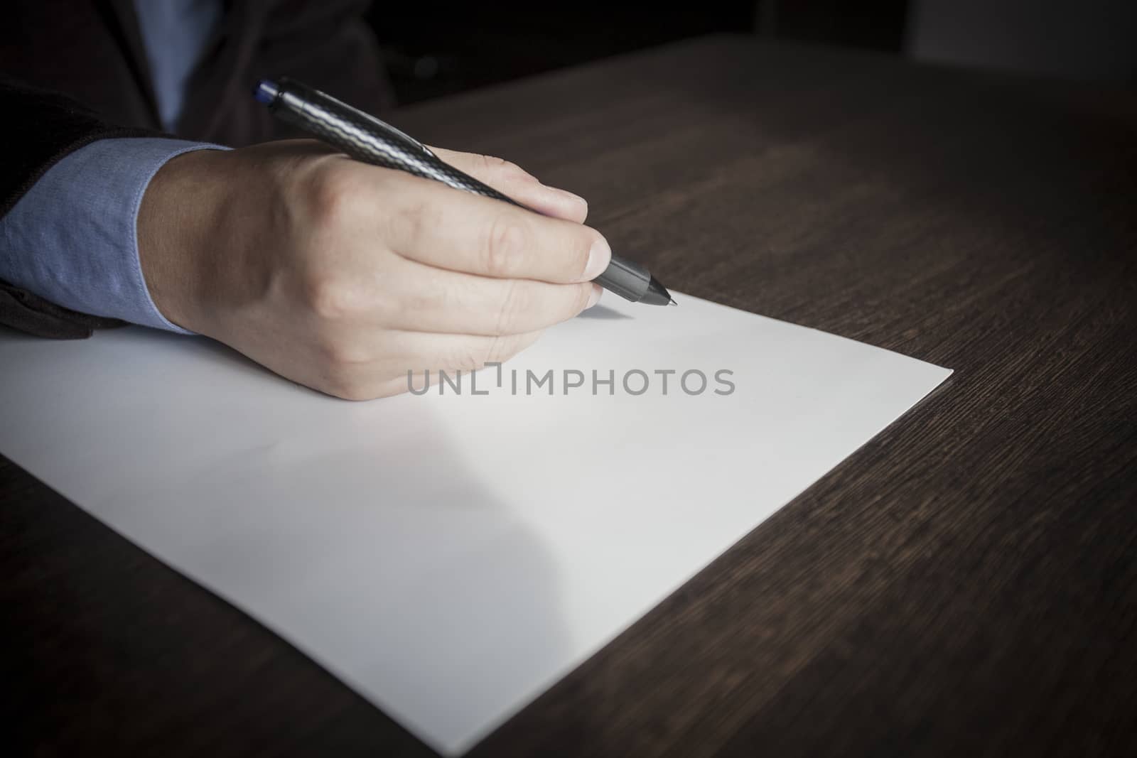 Man's hands keep the handle in a business suit over a sheet of paper