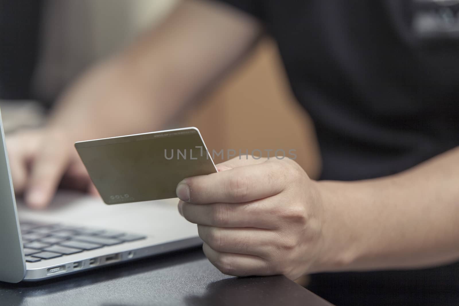 The man with a plastic card sits at the laptop and makes purchase online