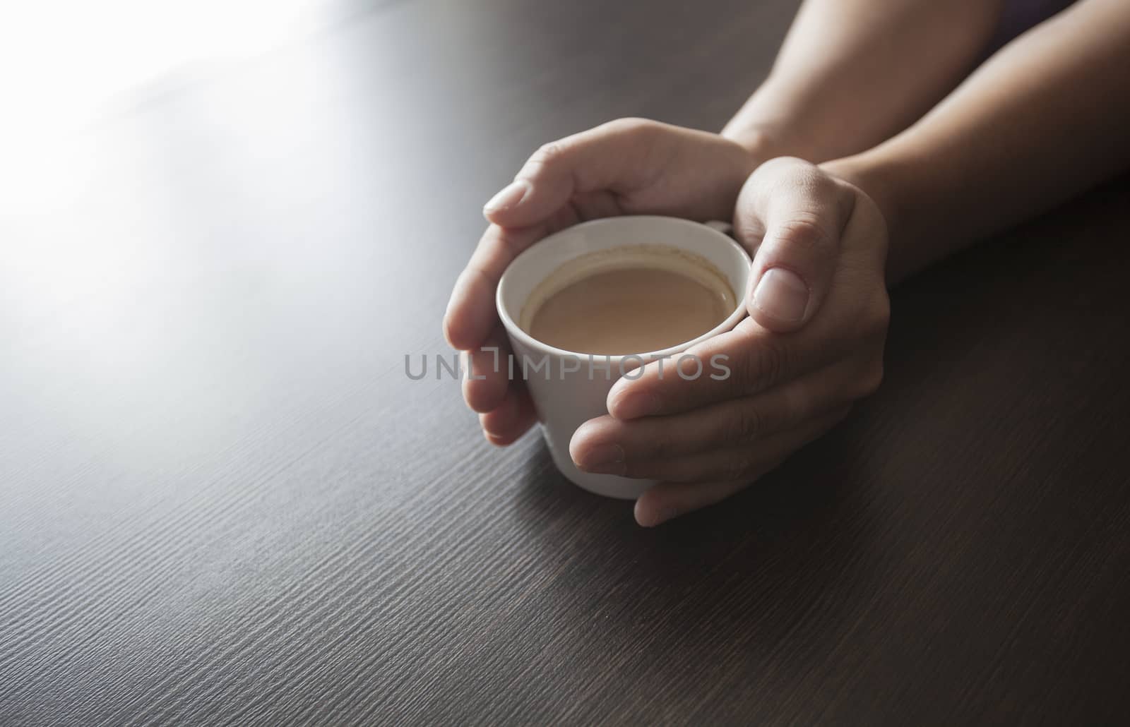 Hands hold a hot cup of coffee on a table