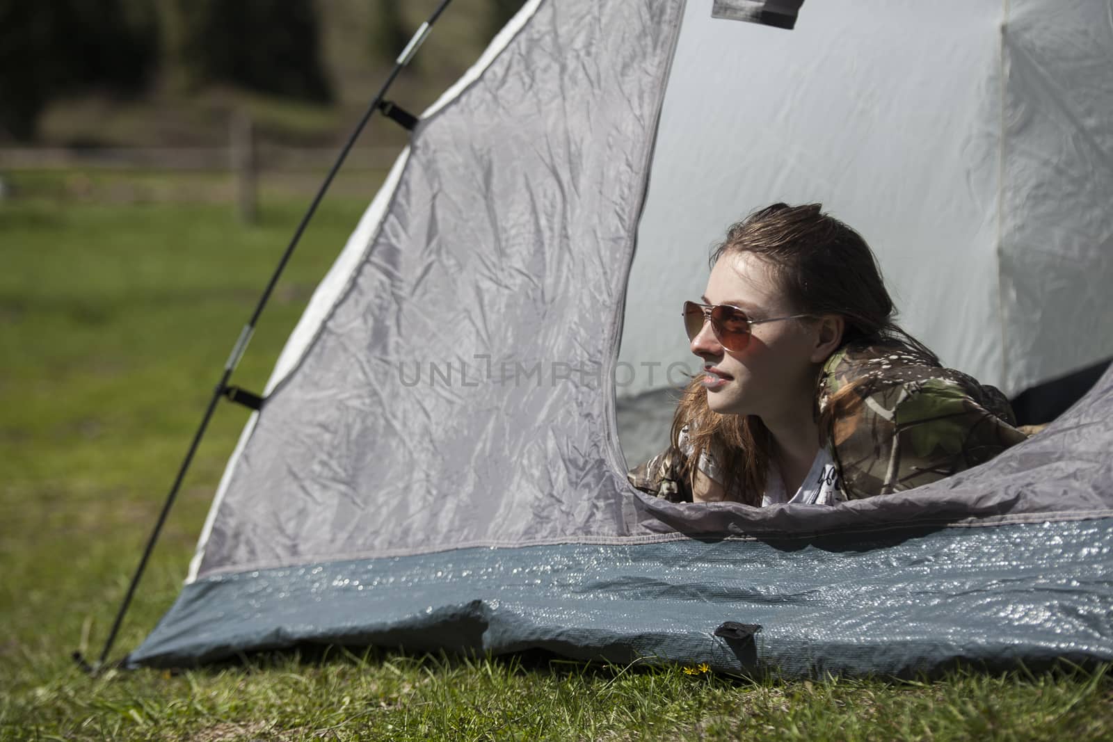 The girl looks out of tent and has a rest