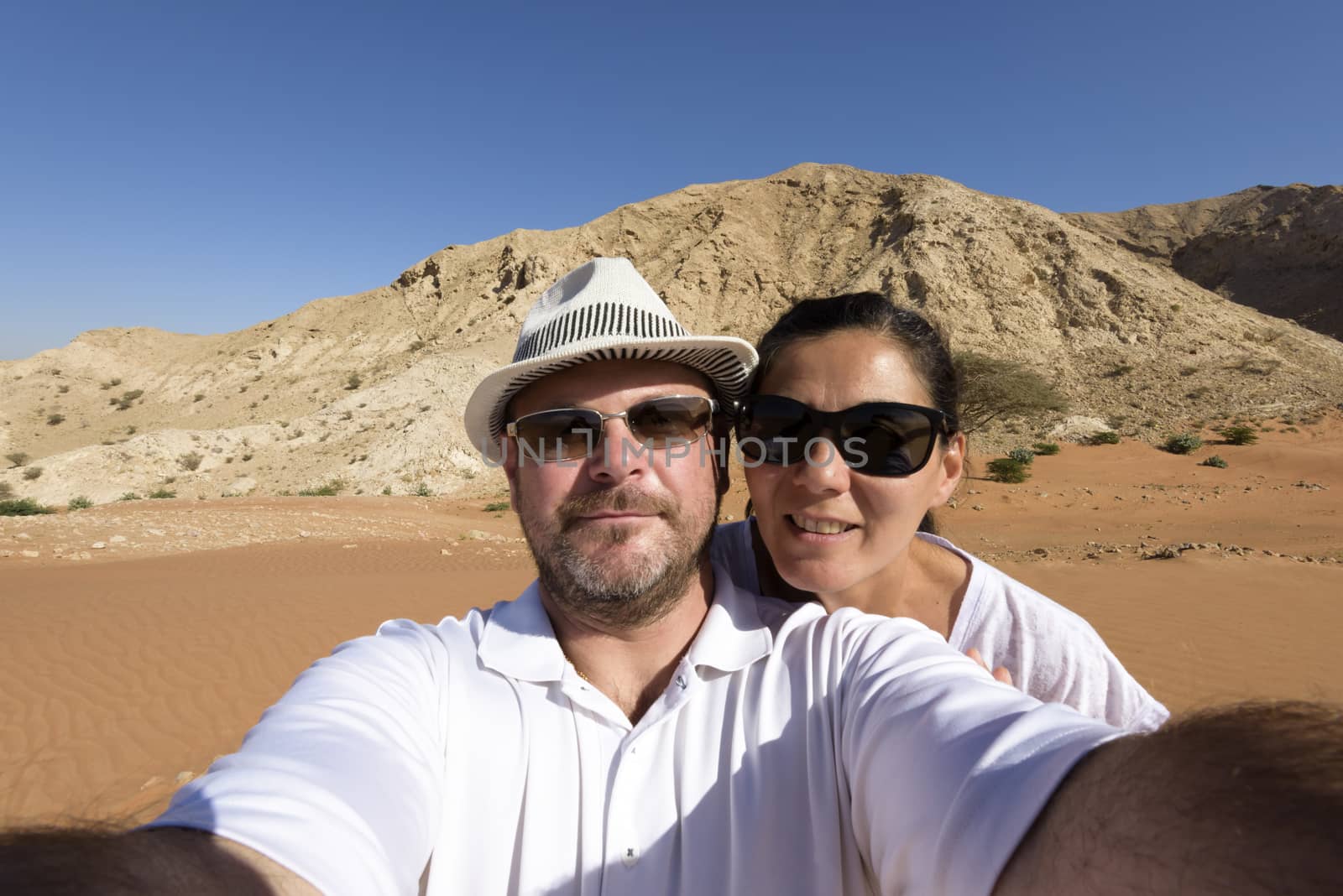 A couple in the 40s taking a selfie in the desert  by GABIS
