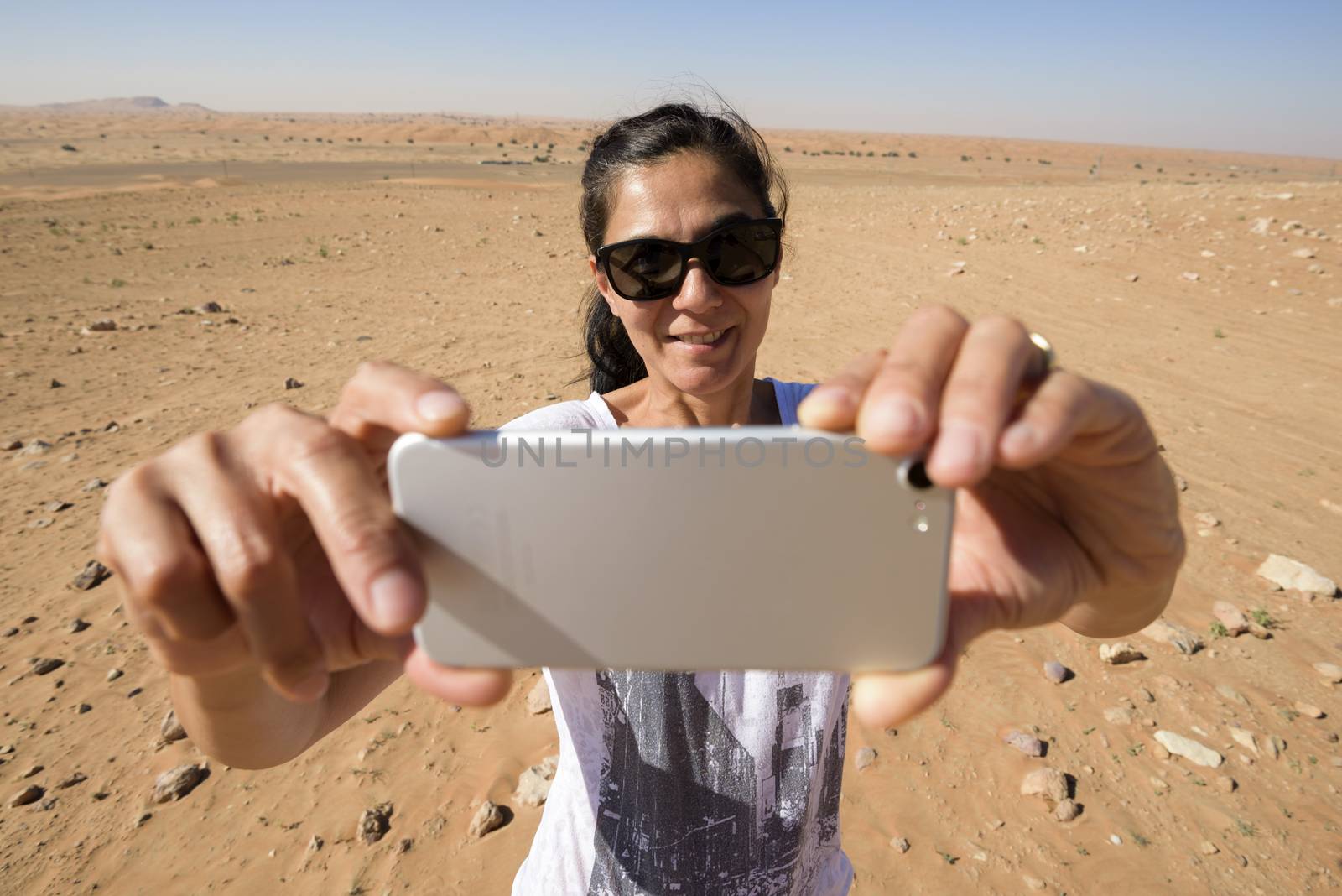 Woman taking a selfie in the desert with her mobile by GABIS