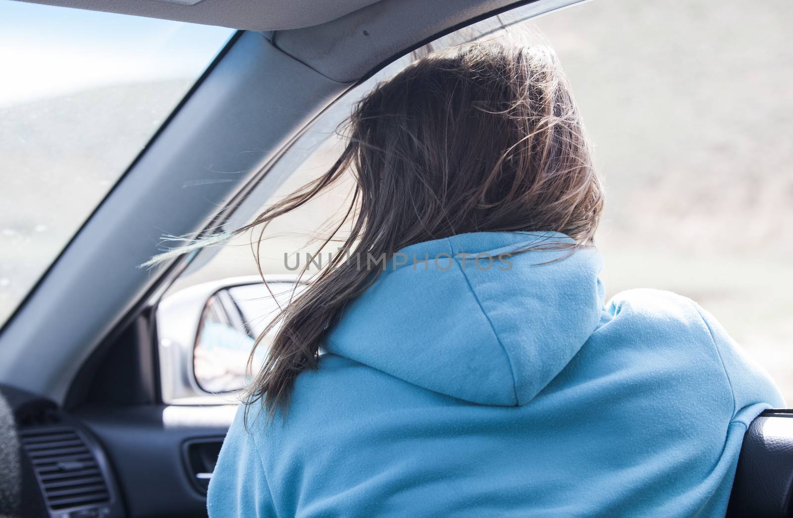 The European girl goes in the car having put out the head in a window