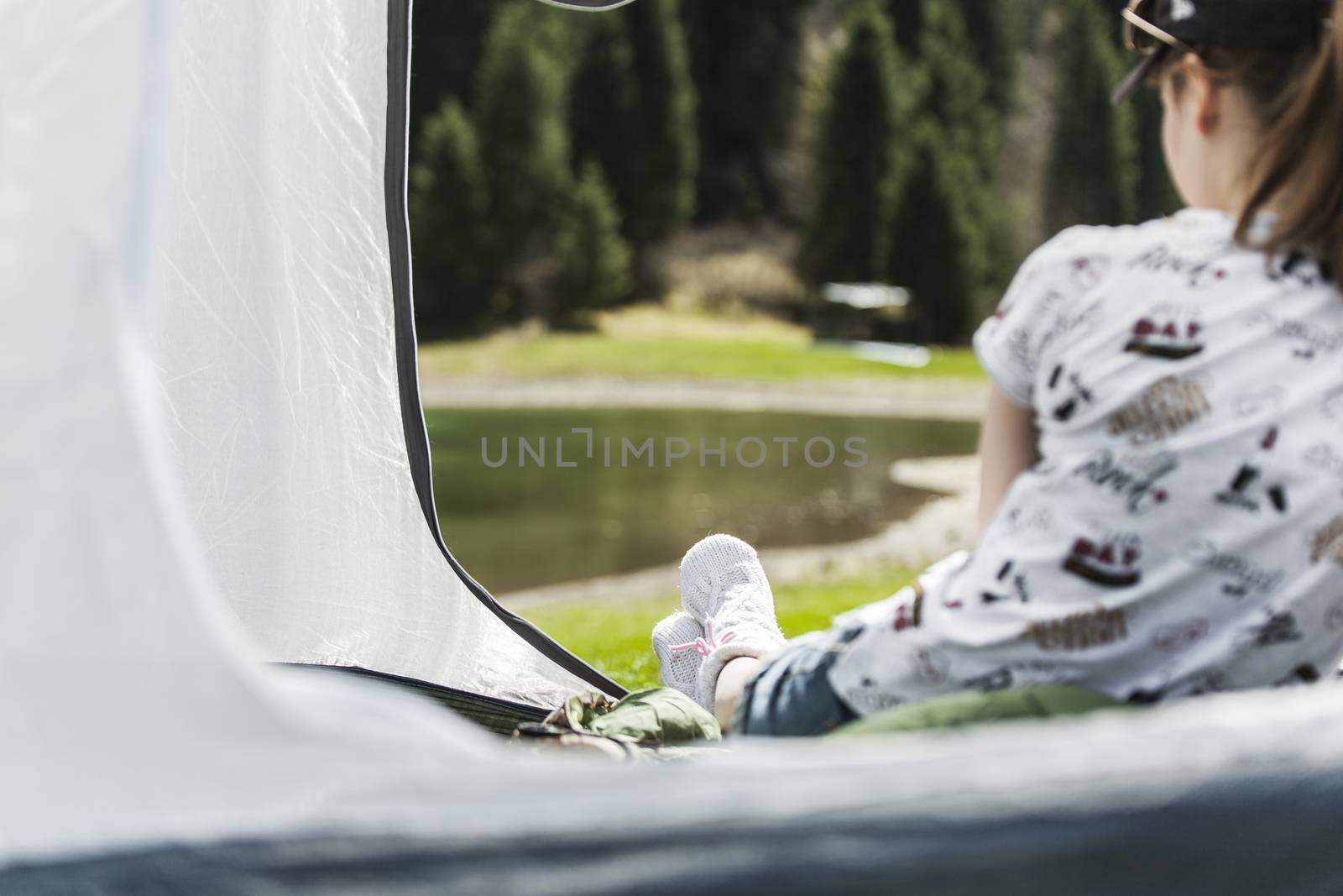 The girl on vacation, sits in tent having put out feet in warm socks