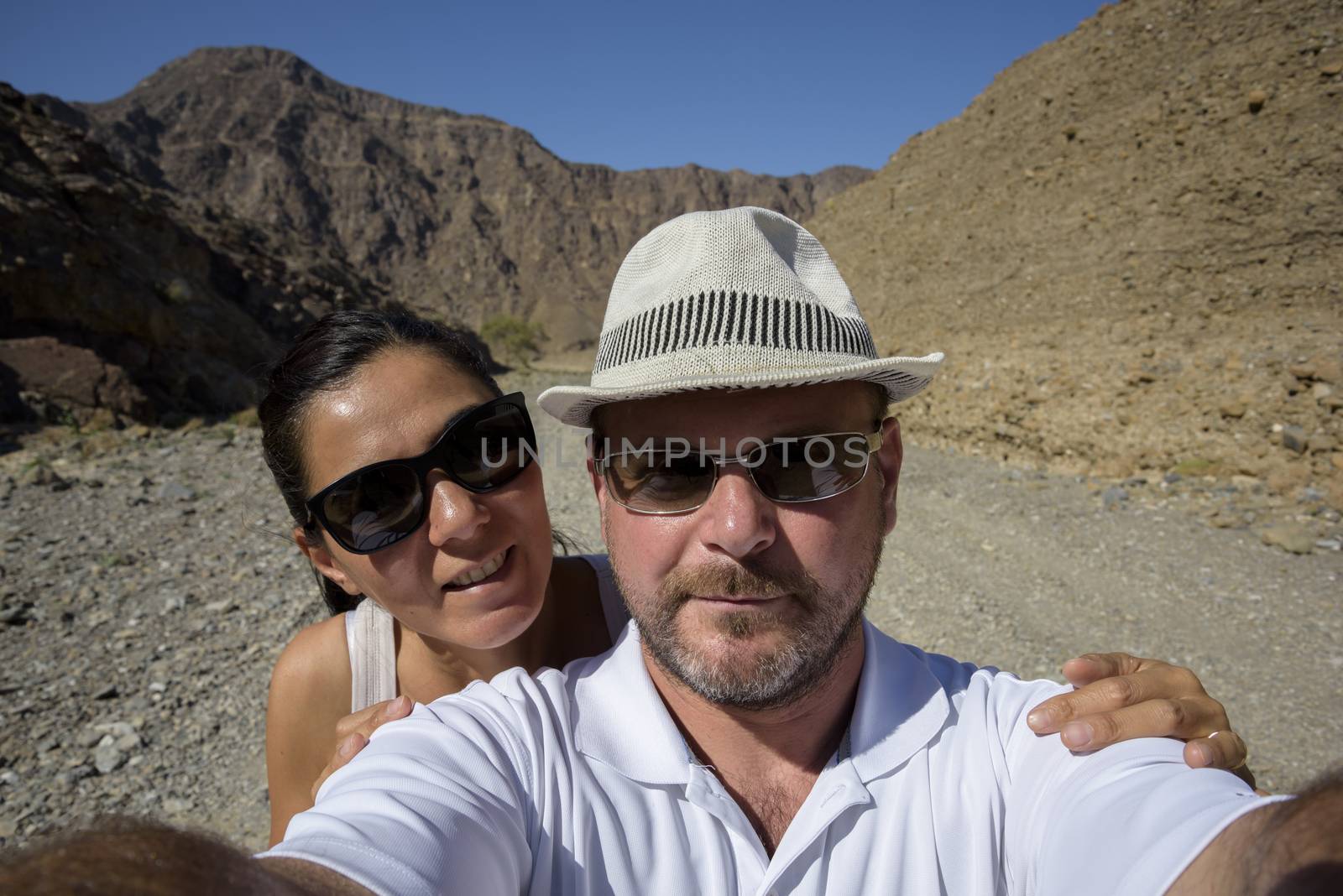 A couple in the 40s taking a selfie in a Wadi (dry riverbed) in the United Arab Emirates.