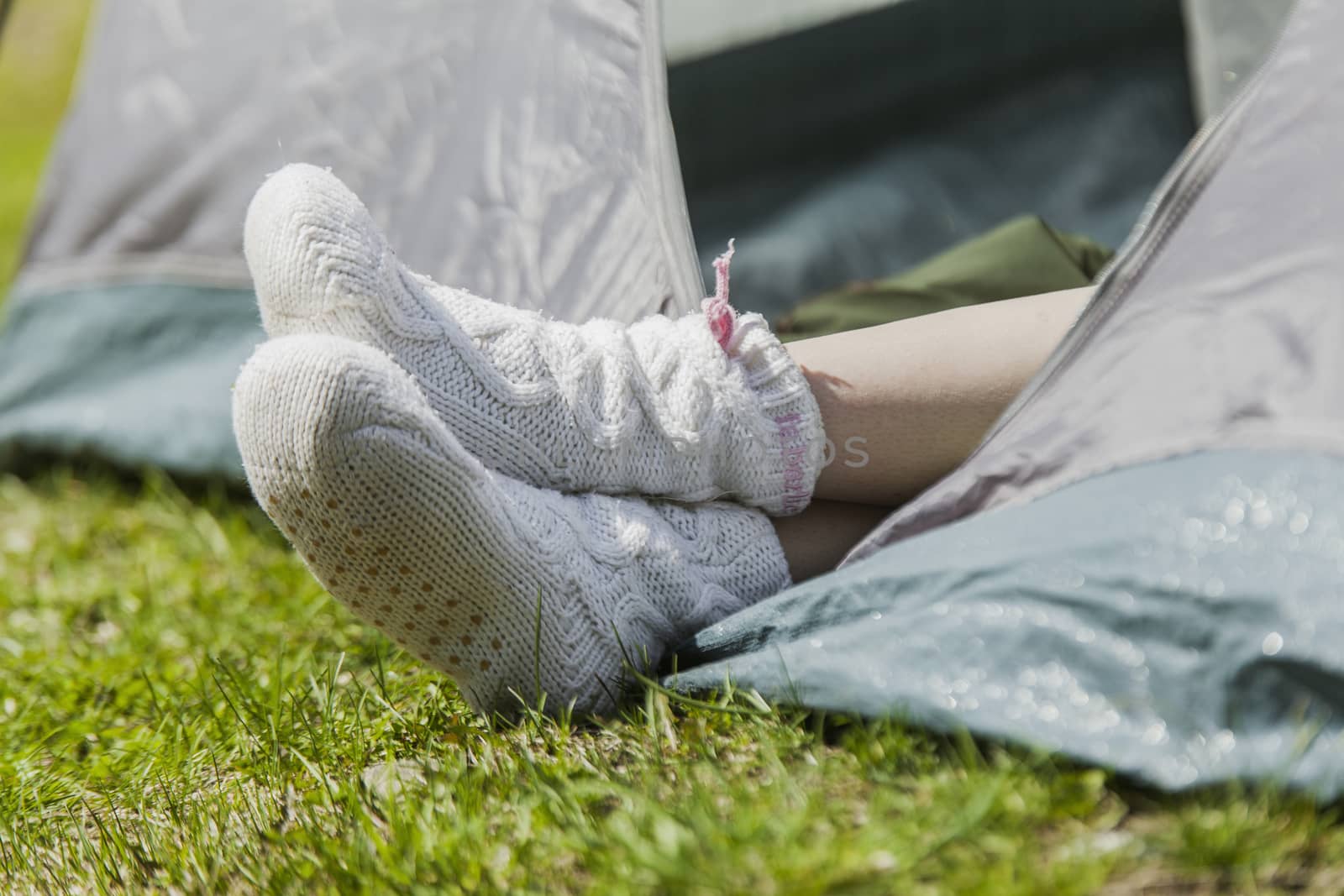 Female feet in warm socks stick out of tent
