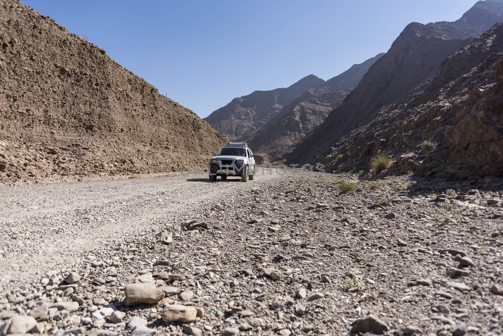 4x4 vehicle in a Wadi (dry riverbed) of Fujairah Emirates, United Arab Emirates.
The small SUV is on a path in a small canyon.