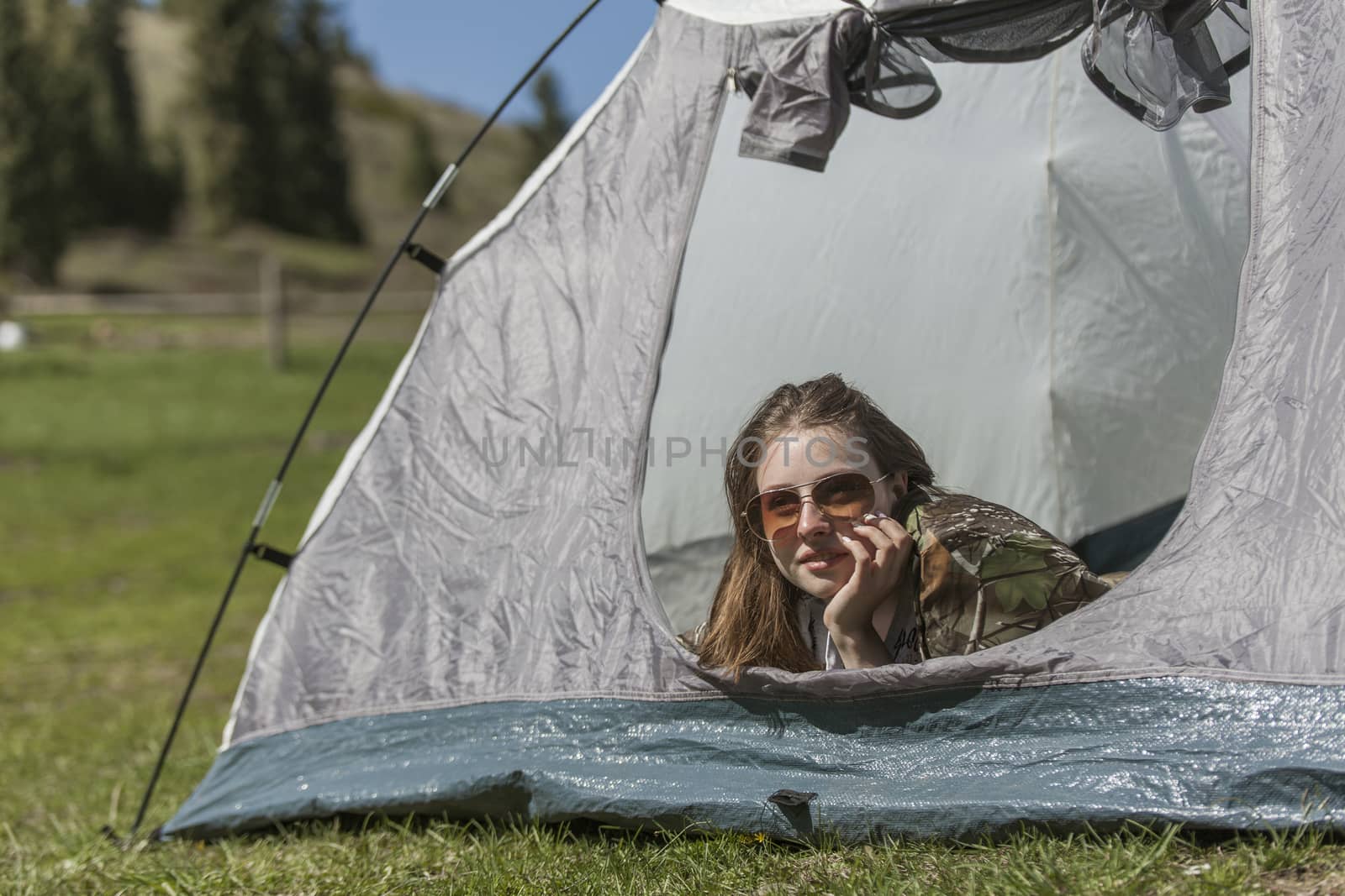 The girl looks out of tent and has a rest