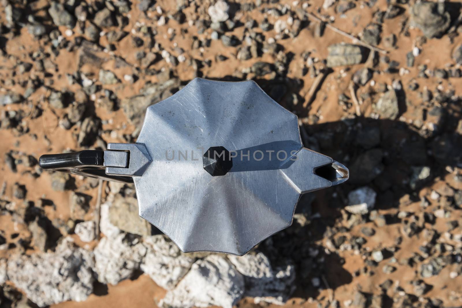 Top view of Italian Coffee maker at a fireplace in the desert, surrounded by sand and stones