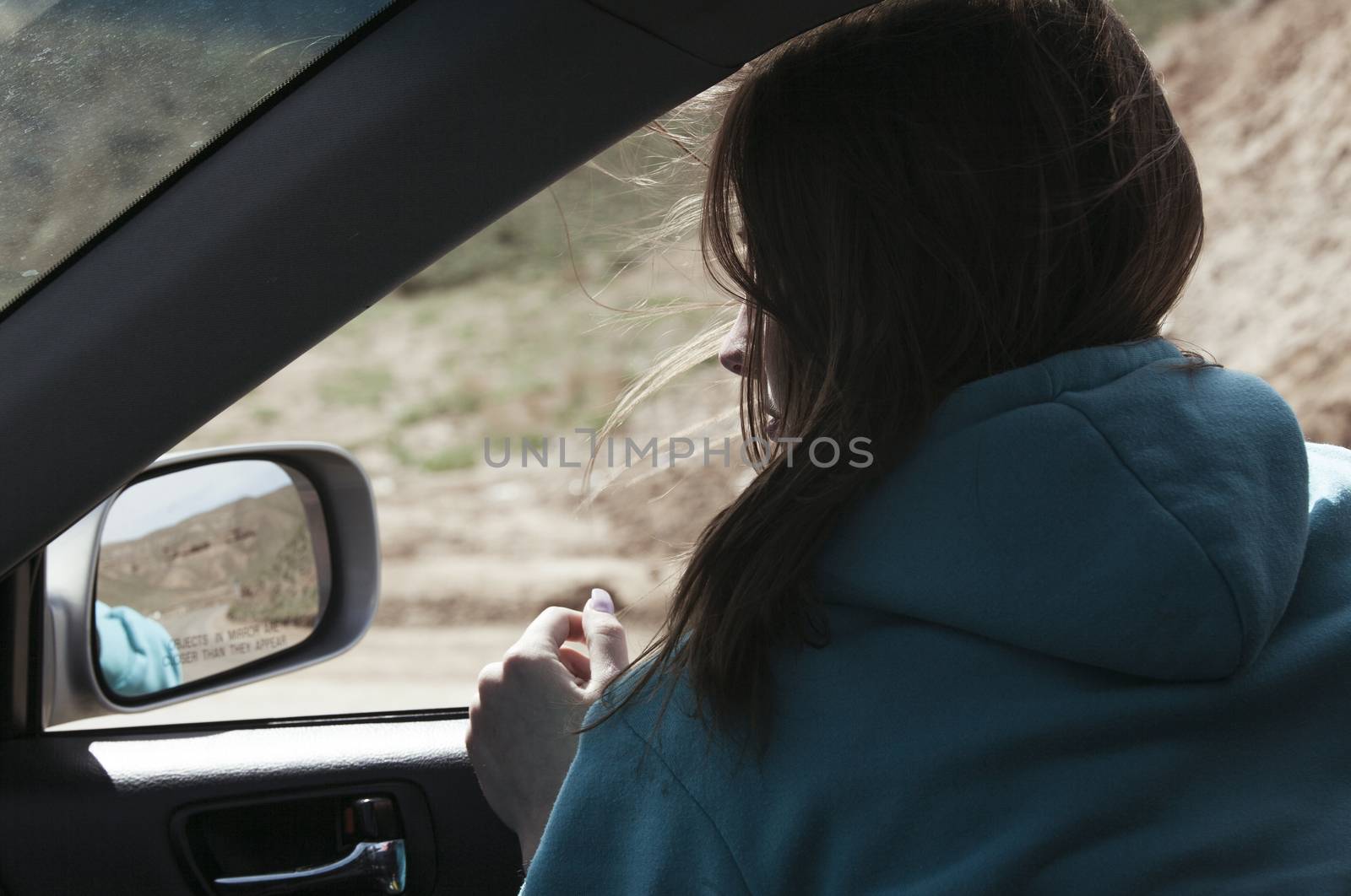 The European girl goes in the car having put out the head in a window