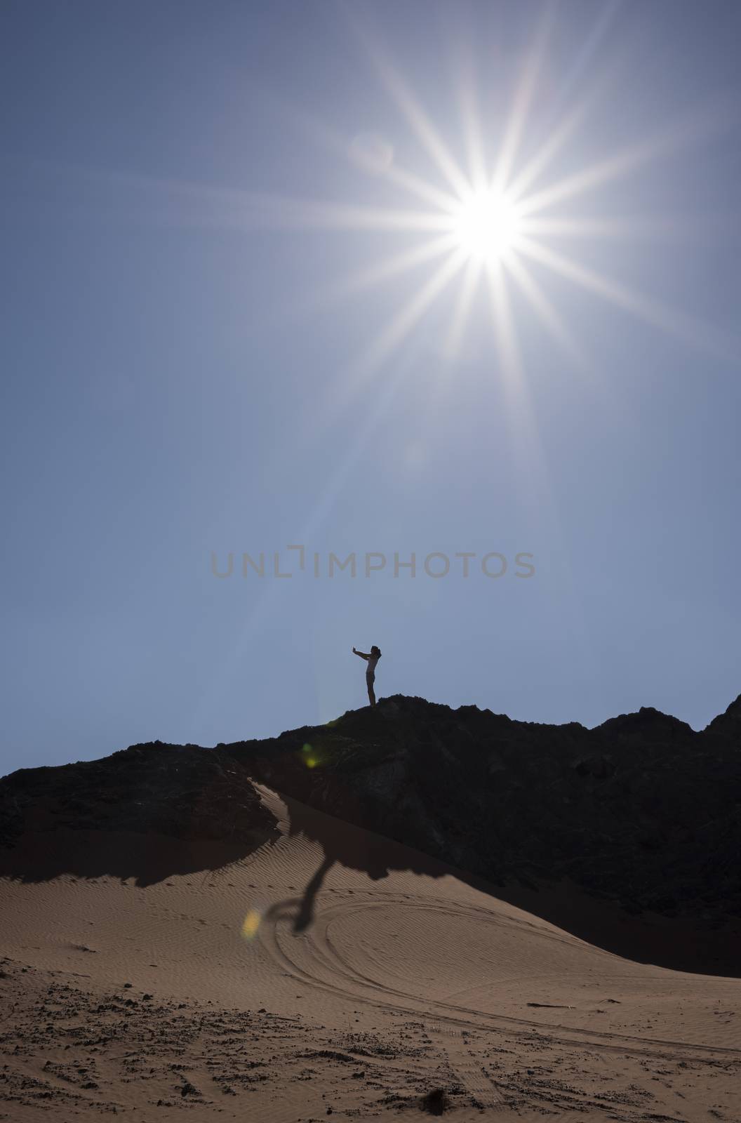 Woman taking a selfie in a mountain in the desert with contre-jour.