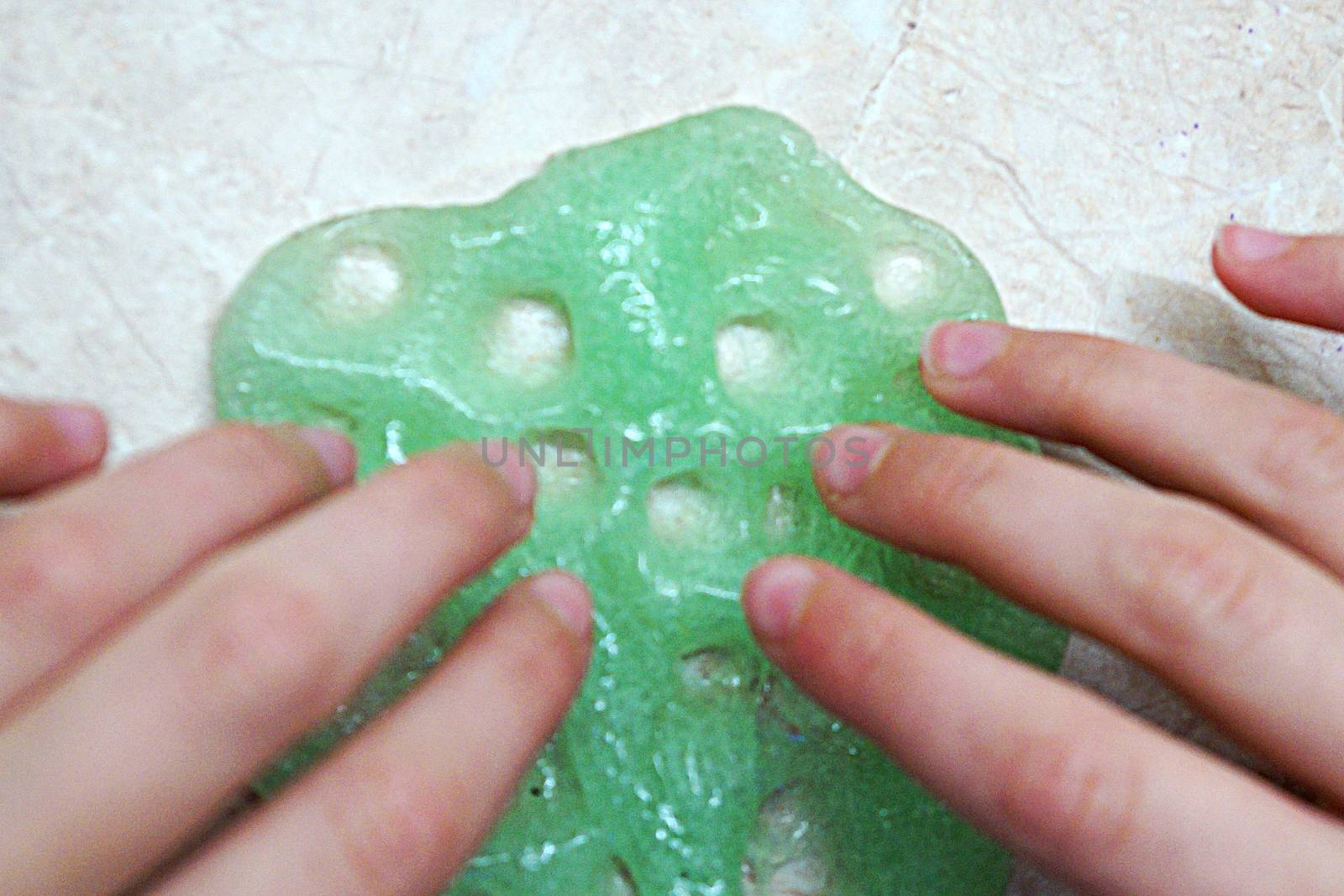 children's hands play with green slime close up