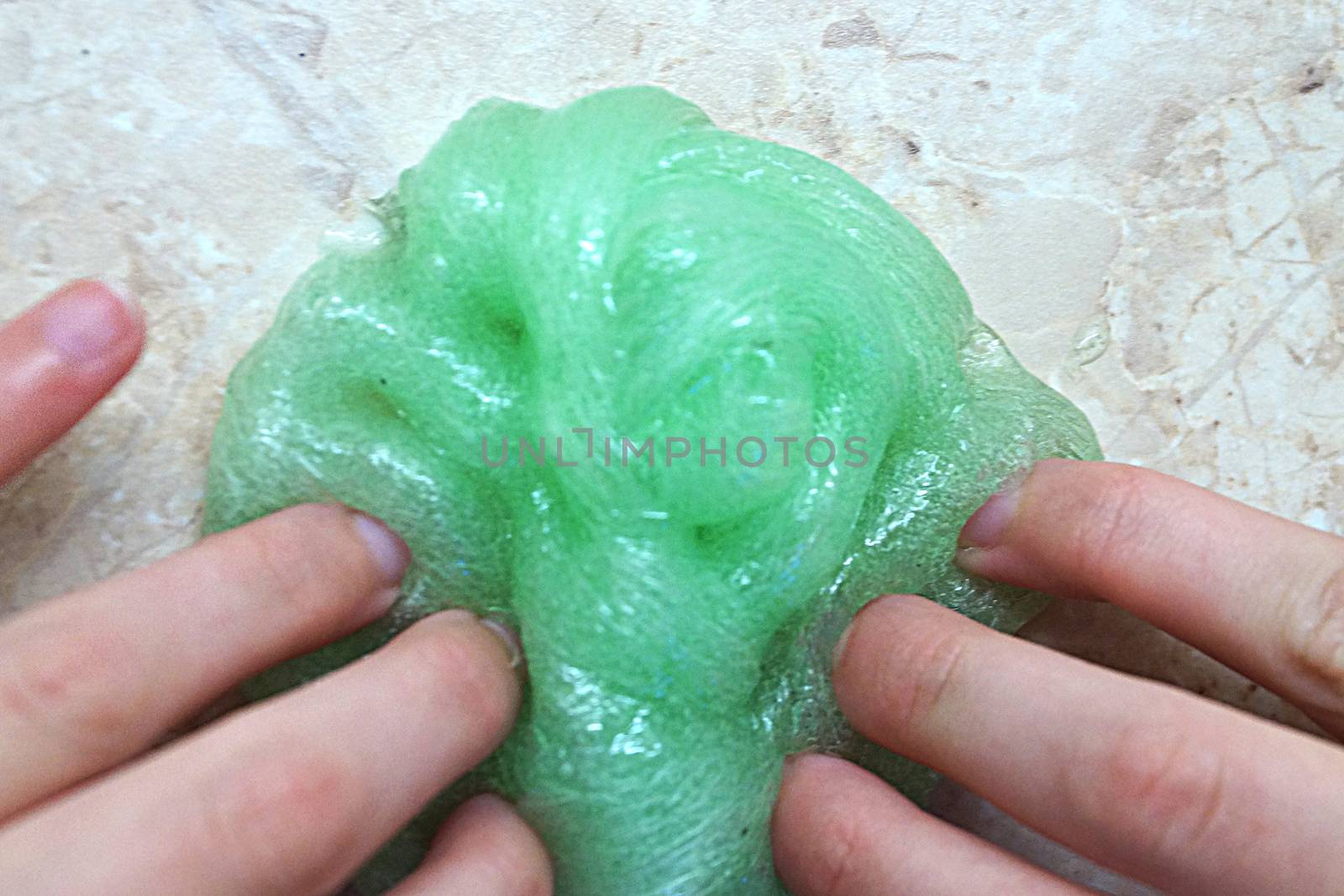 children's hands play with green slime close up. by Annado