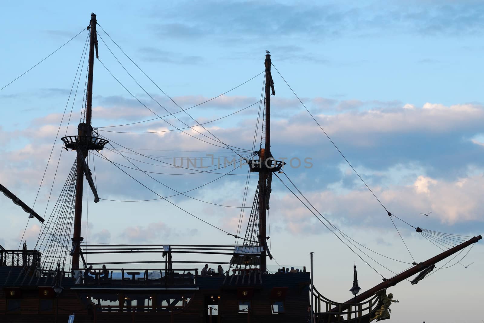 open-air restaurant on the deck of an old ship, silhouette against the sky. by Annado