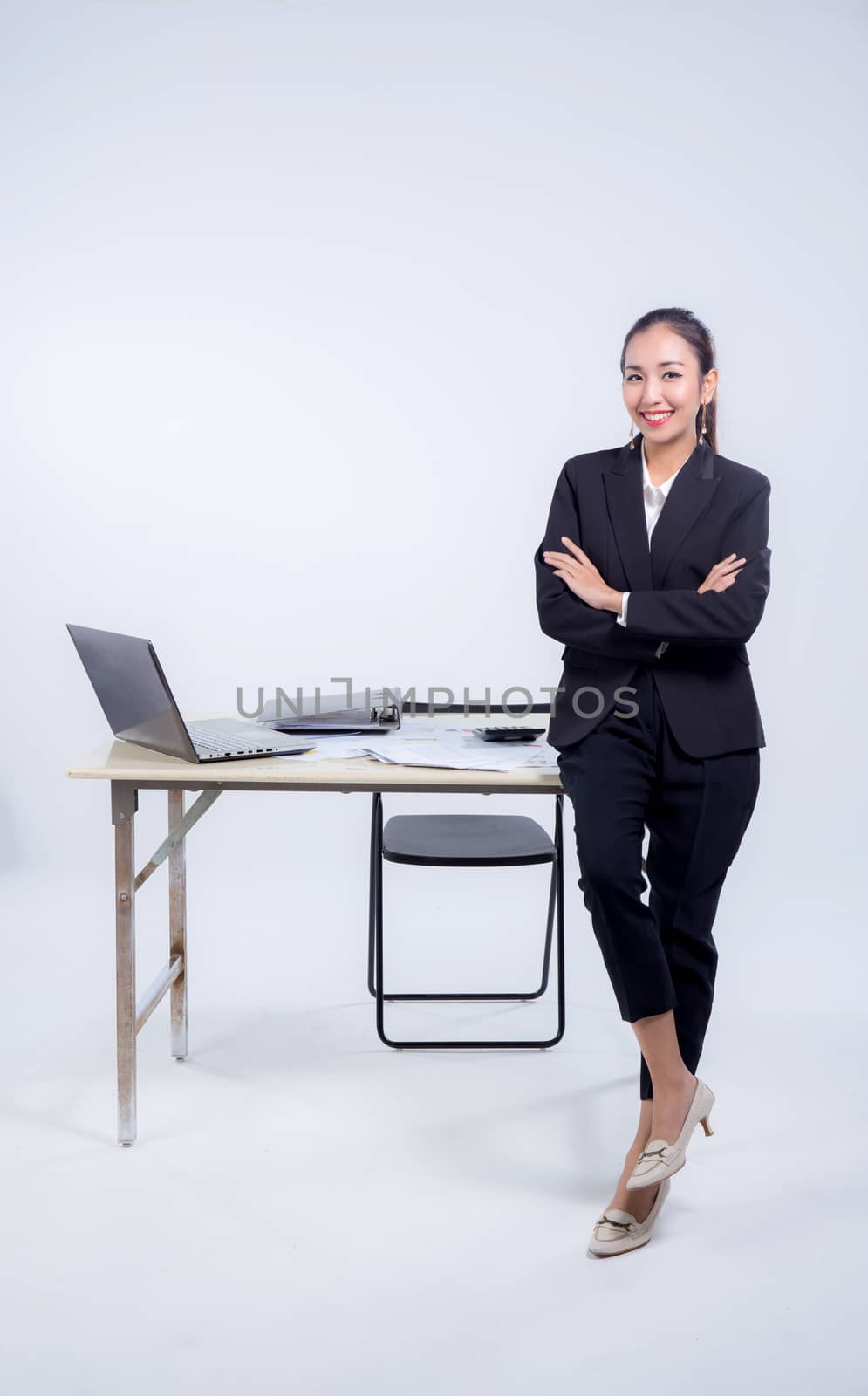 Confident businesswoman in office smiling at the camera with folded arms in office.