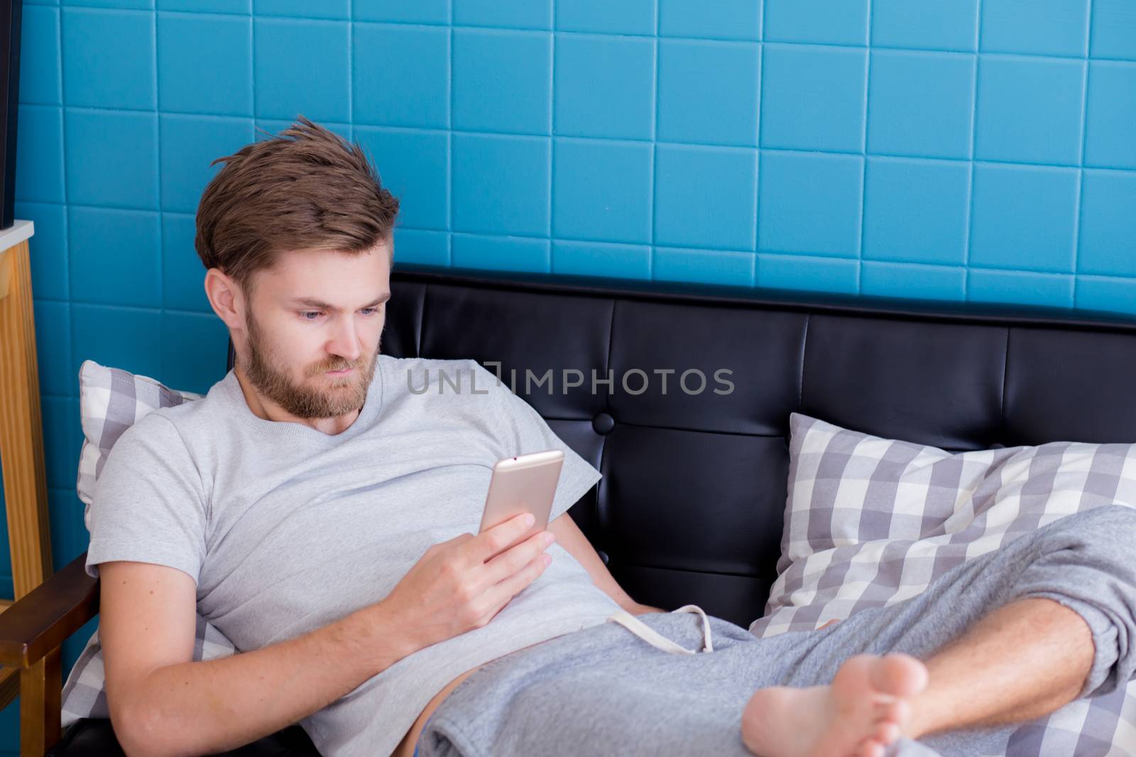 Happy man watching media content in a smart phone sitting on a couch at home.