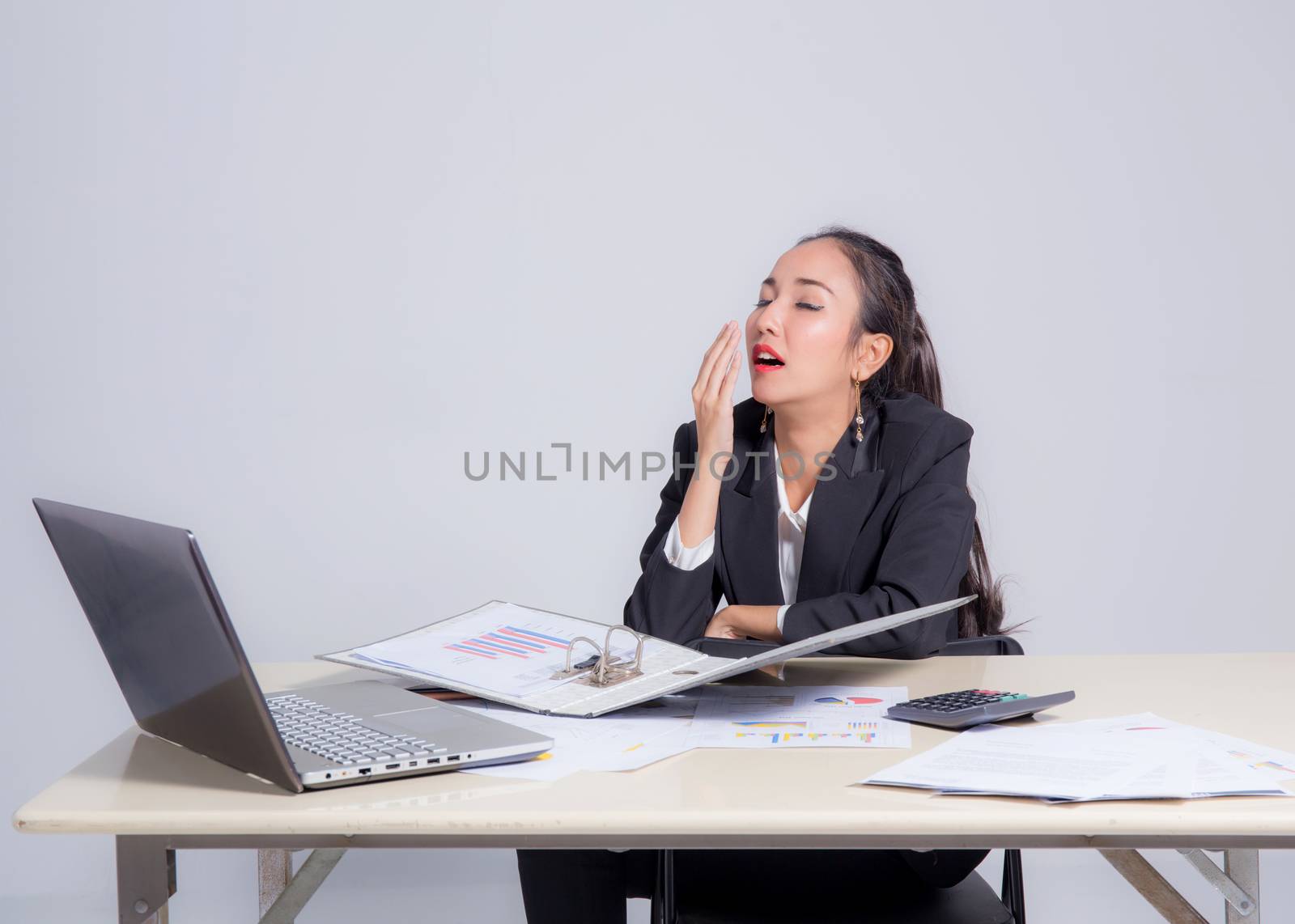 Tired sleepy woman yawning - working at office desk overwork and sleep deprivation concept.