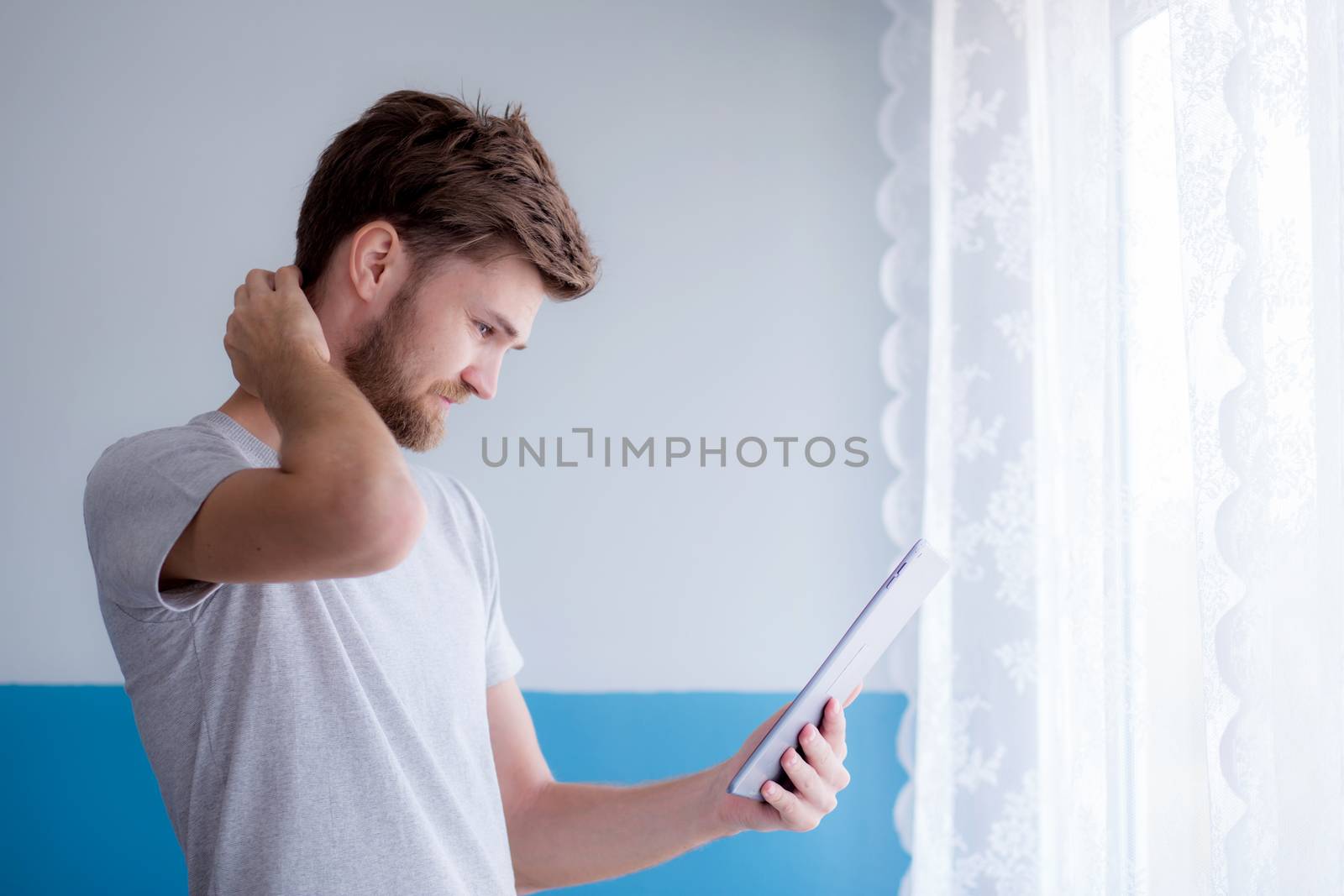 bearded man using tablet while standing near the window in his modern apartment.Concept young business people working at home.